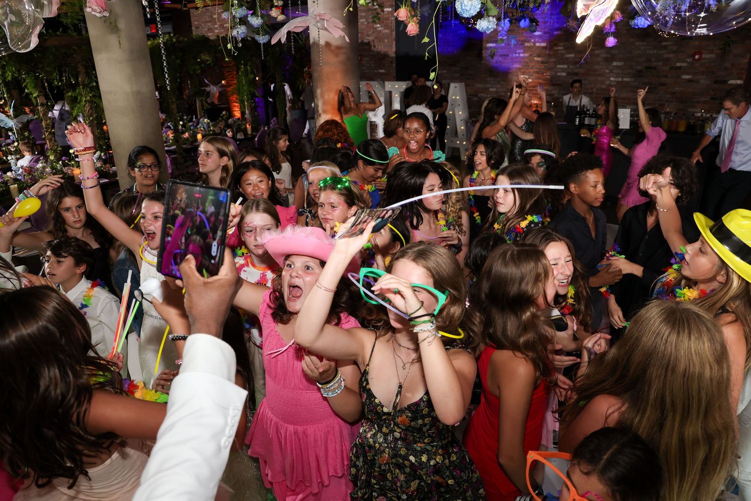 Colorful Mardi Gras party with costumed guests dancing, wearing beads and festive hats at a lively indoor celebration.