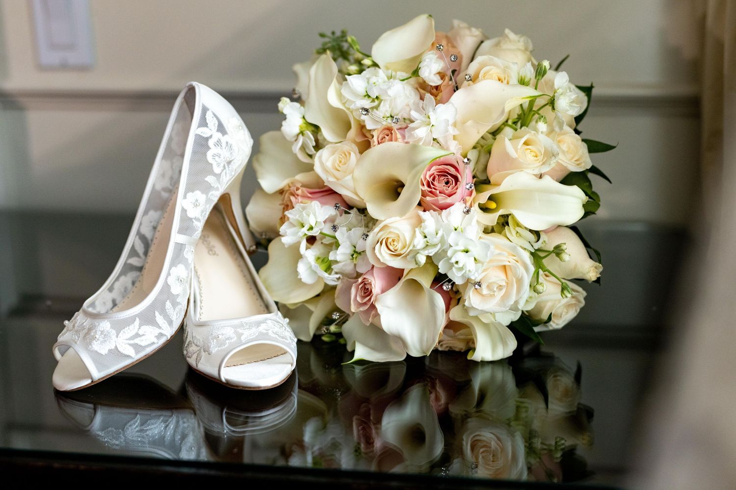 Wedding accessories including white floral bouquet, shoes, and roses arranged artistically.
