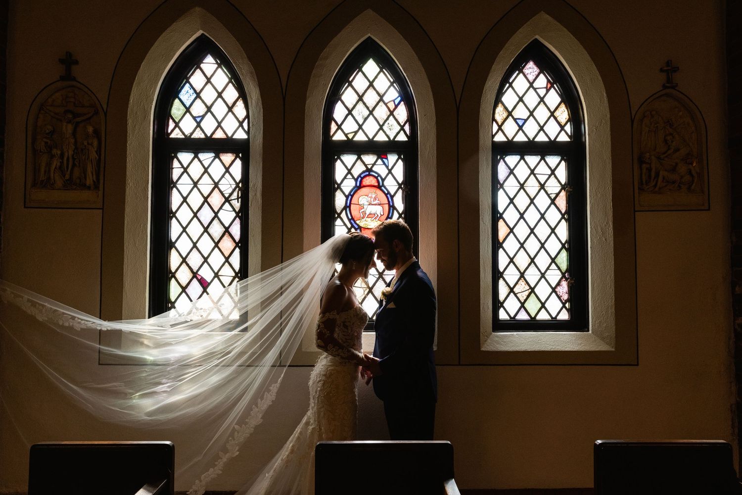 Gothic arched windows create dramatic lighting in an elegant wedding venue.