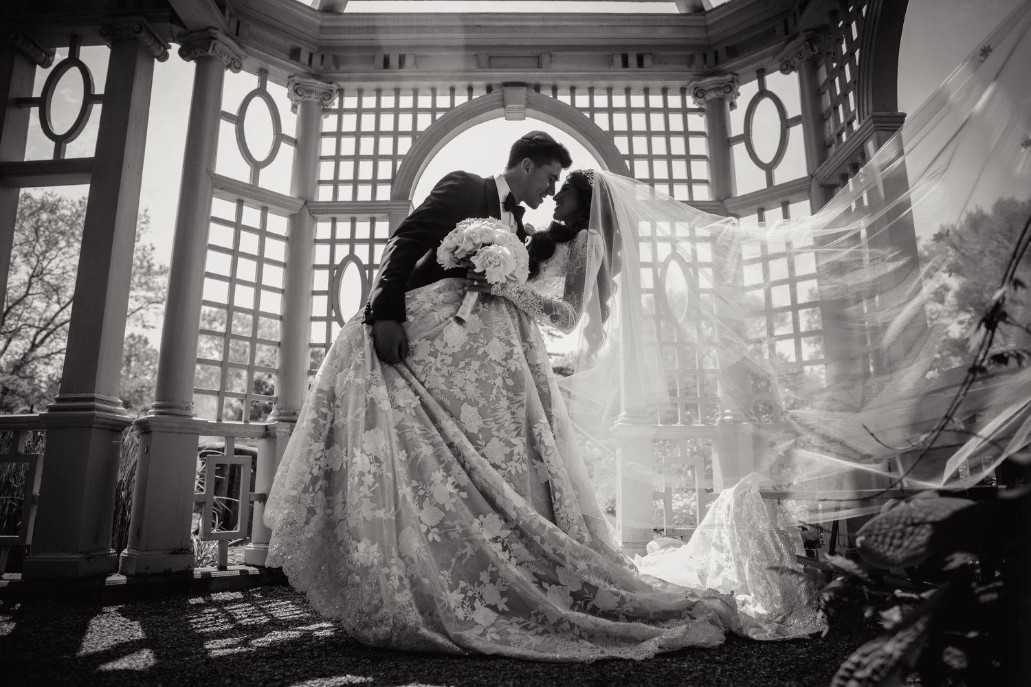 Elegant wedding couple poses in architectural setting with dramatic lighting and geometric patterns.
