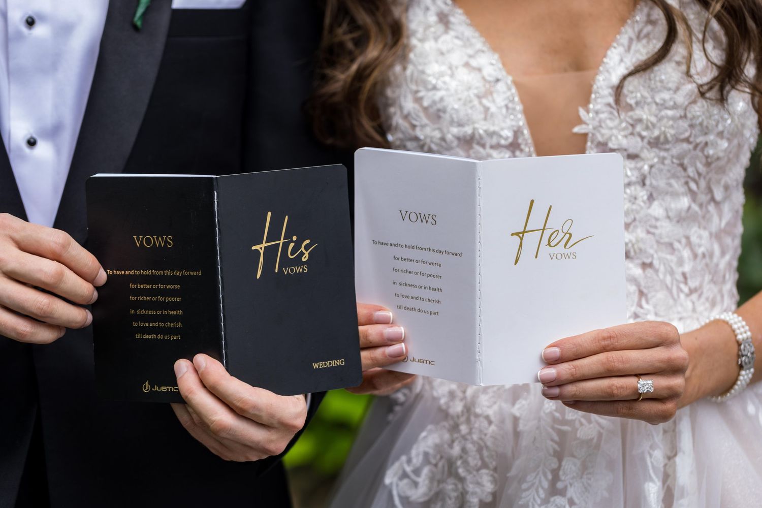 Wedding couple holding personalized vow books with gold lettering.
