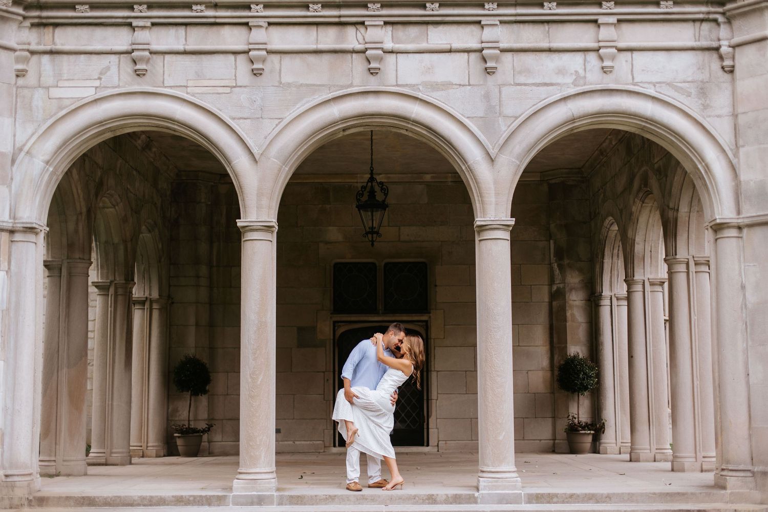 A romantic moment captured under elegant stone archways of a historic building.