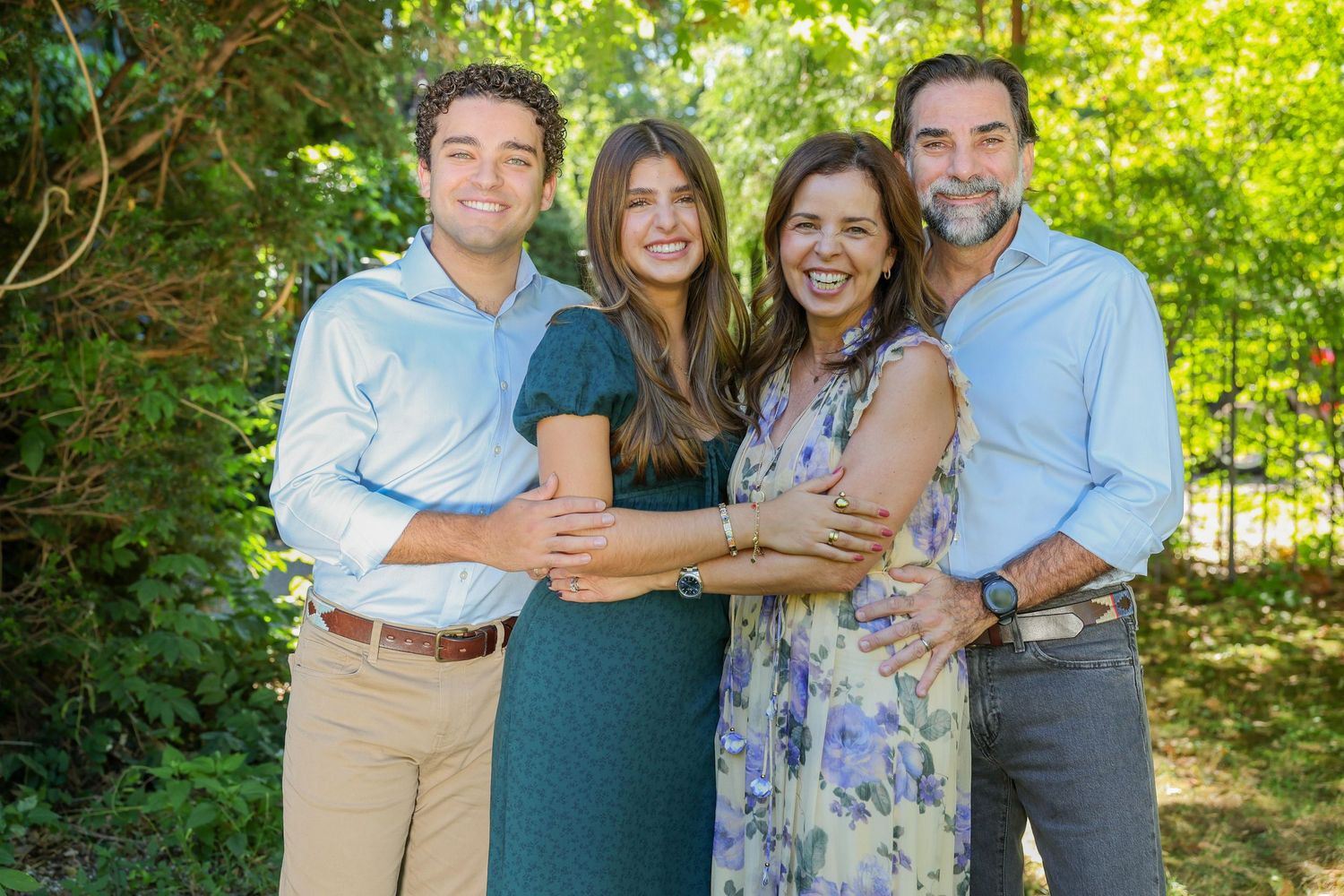 Family members embrace while posing for outdoor portraits in a garden setting.