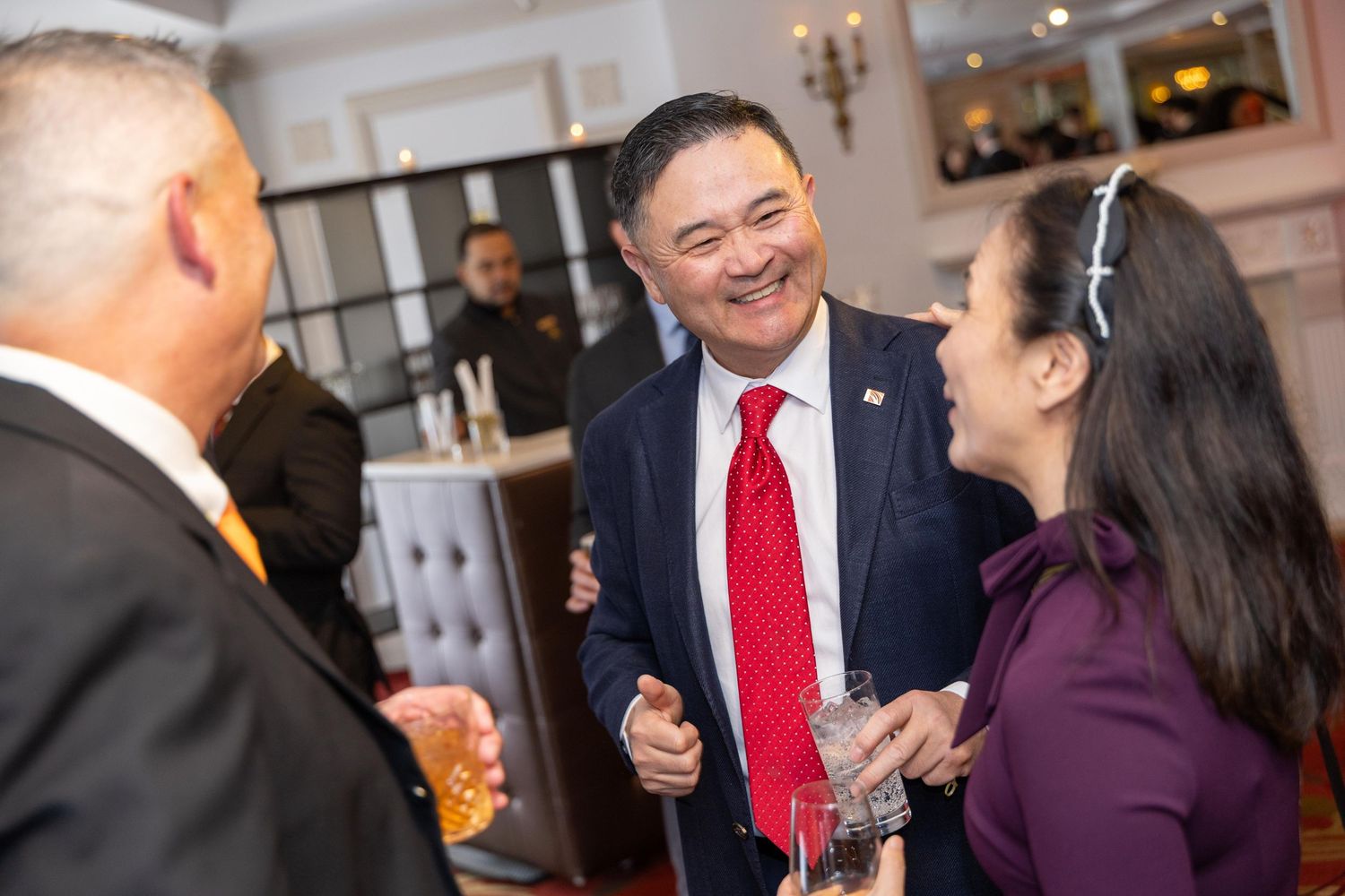 Professionals in formal attire networking and smiling at a corporate social event.