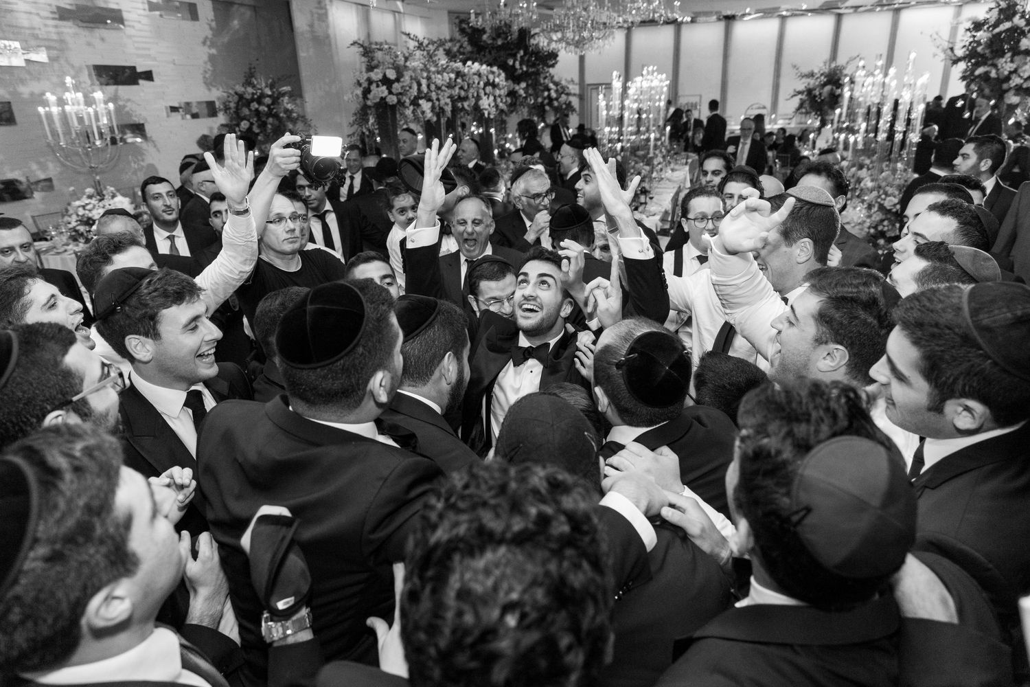 Large crowd of wedding guests gathered in circle during festive celebration.