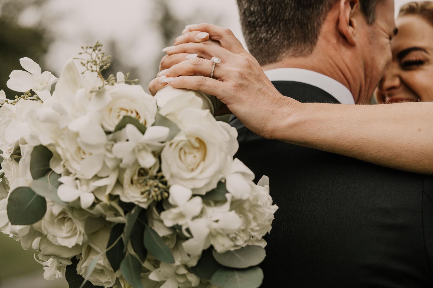 An intimate wedding moment with white rose bouquet in the foreground.
