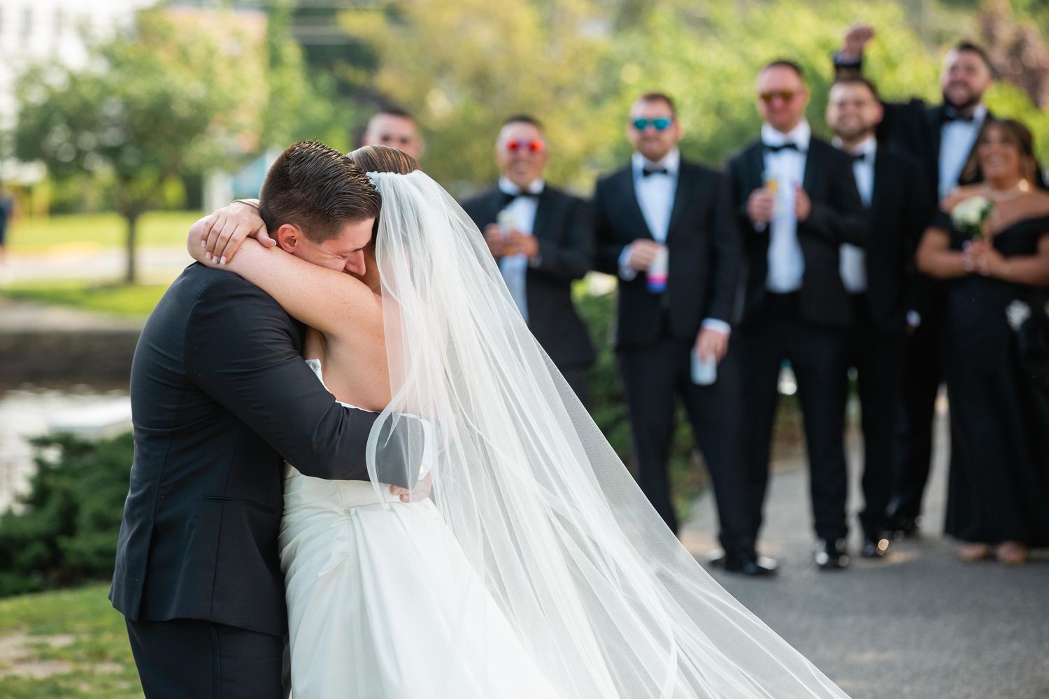 Wedding party celebrating with joyful embraces during an outdoor garden ceremony.