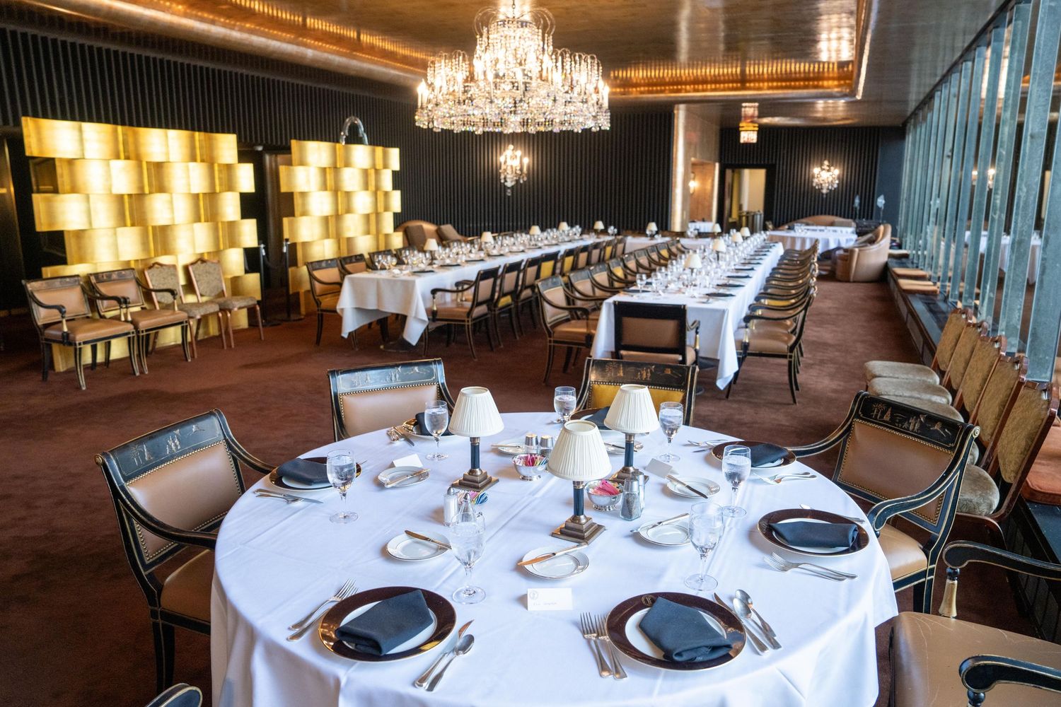 Elegant banquet hall with round tables set for a formal dinner under crystal chandeliers.