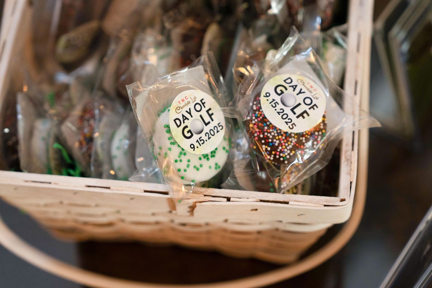 Personalized Day of Golf cookie favors dated 9.17.2022 displayed in a wicker basket.
