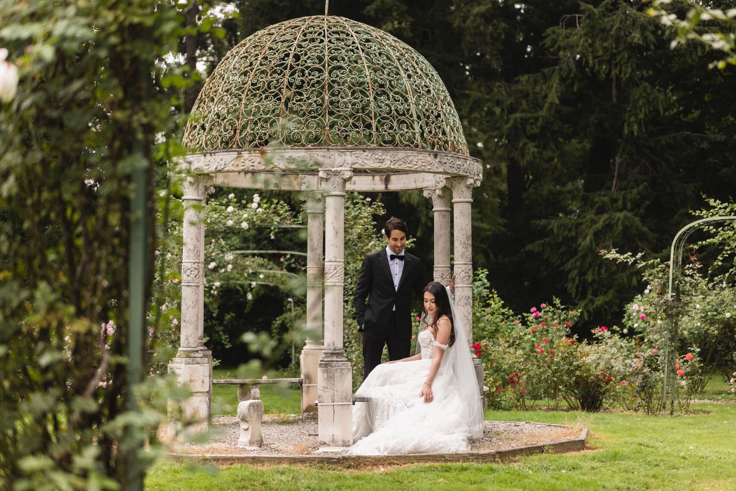 Garden wedding venue with stone gazebo and floral decorations.