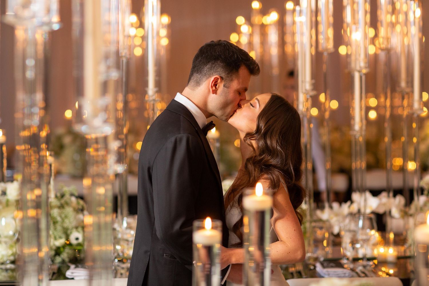 Romantic couple shares intimate moment surrounded by glowing candlelight and crystal decor.