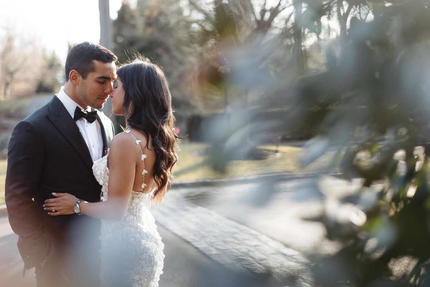 A romantic wedding portrait with soft sunlight and dreamy bokeh effects in the background.