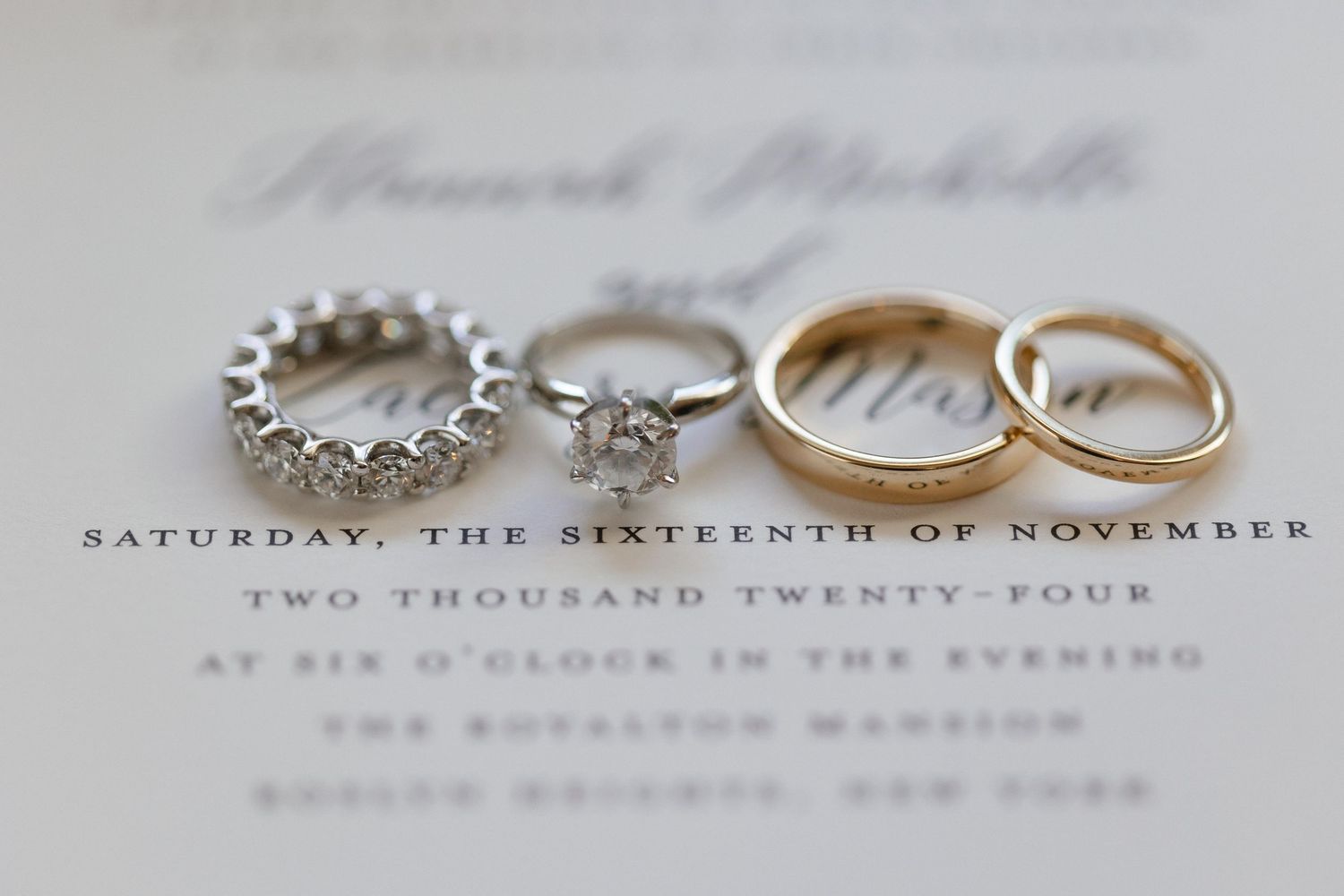 Wedding rings and invitation details photographed in soft focus.