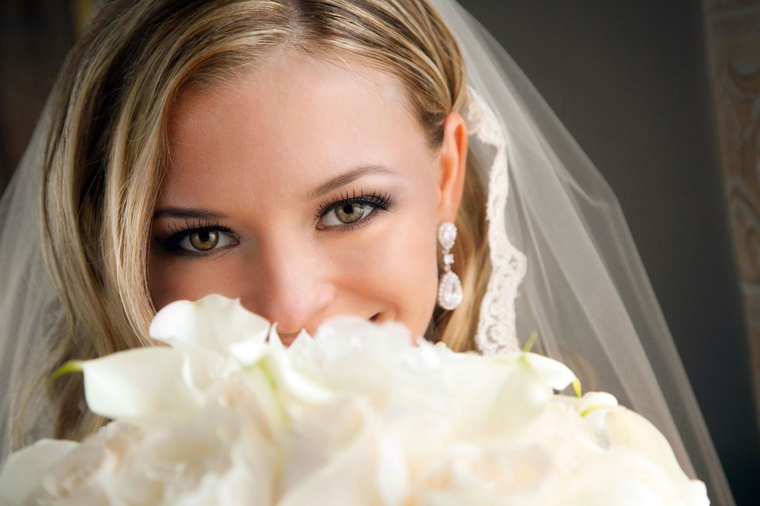 Close-up bridal portrait with white rose bouquet and delicate veil details.
