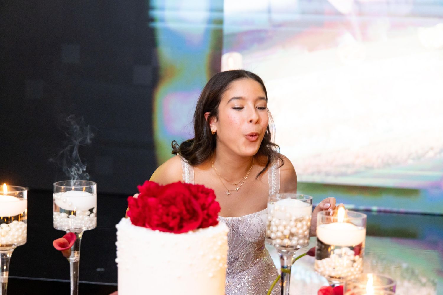 Celebration scene with cake, candles and red floral decorations.