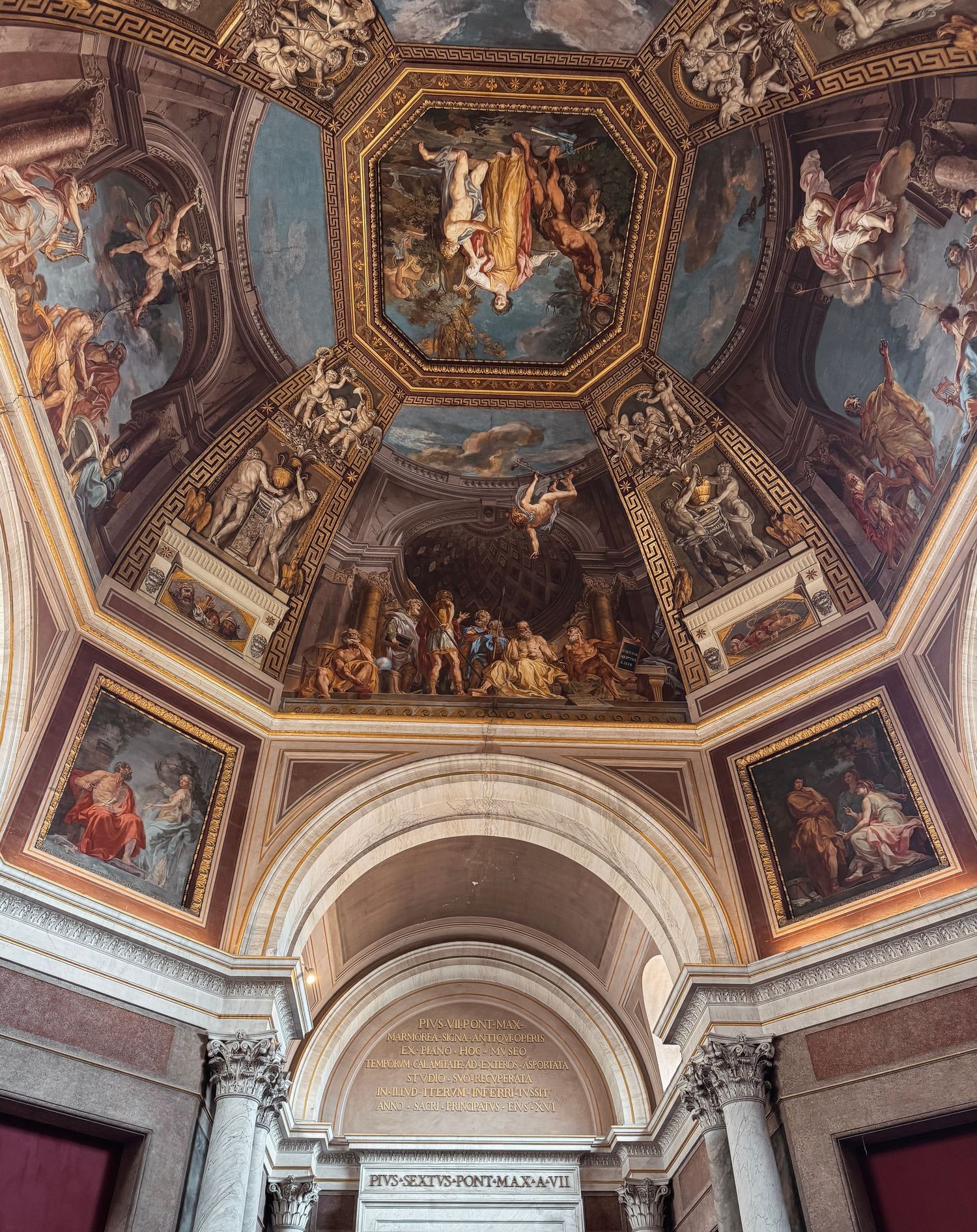 Ornate Baroque ceiling frescoes and gilded frames adorn the interior of a historic palace or church.