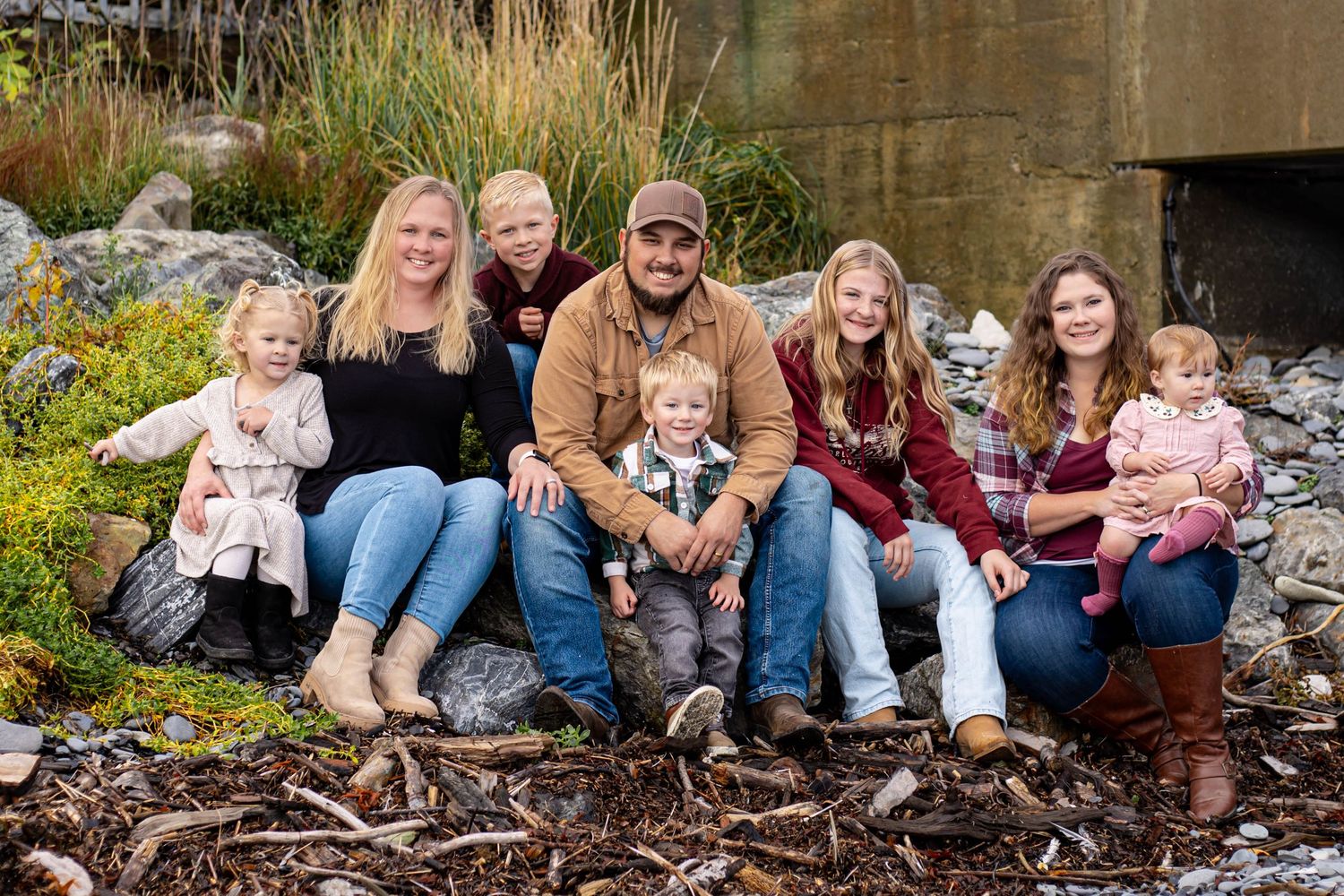 A happy family of seven poses together outdoors on a rocky landscape during autumn.