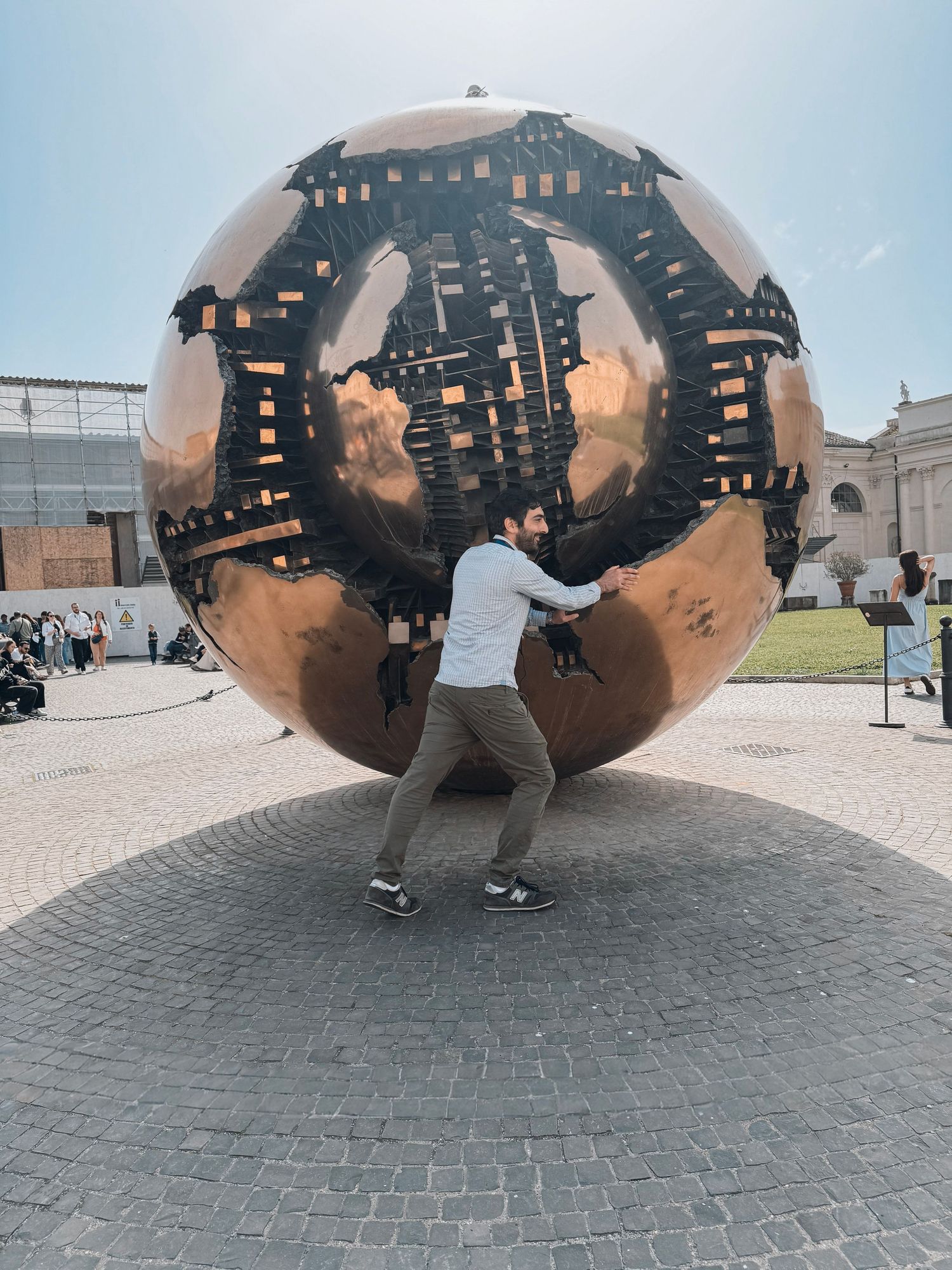 Visitors interact with the spherical Arnaldo Pomodoro sculpture 
