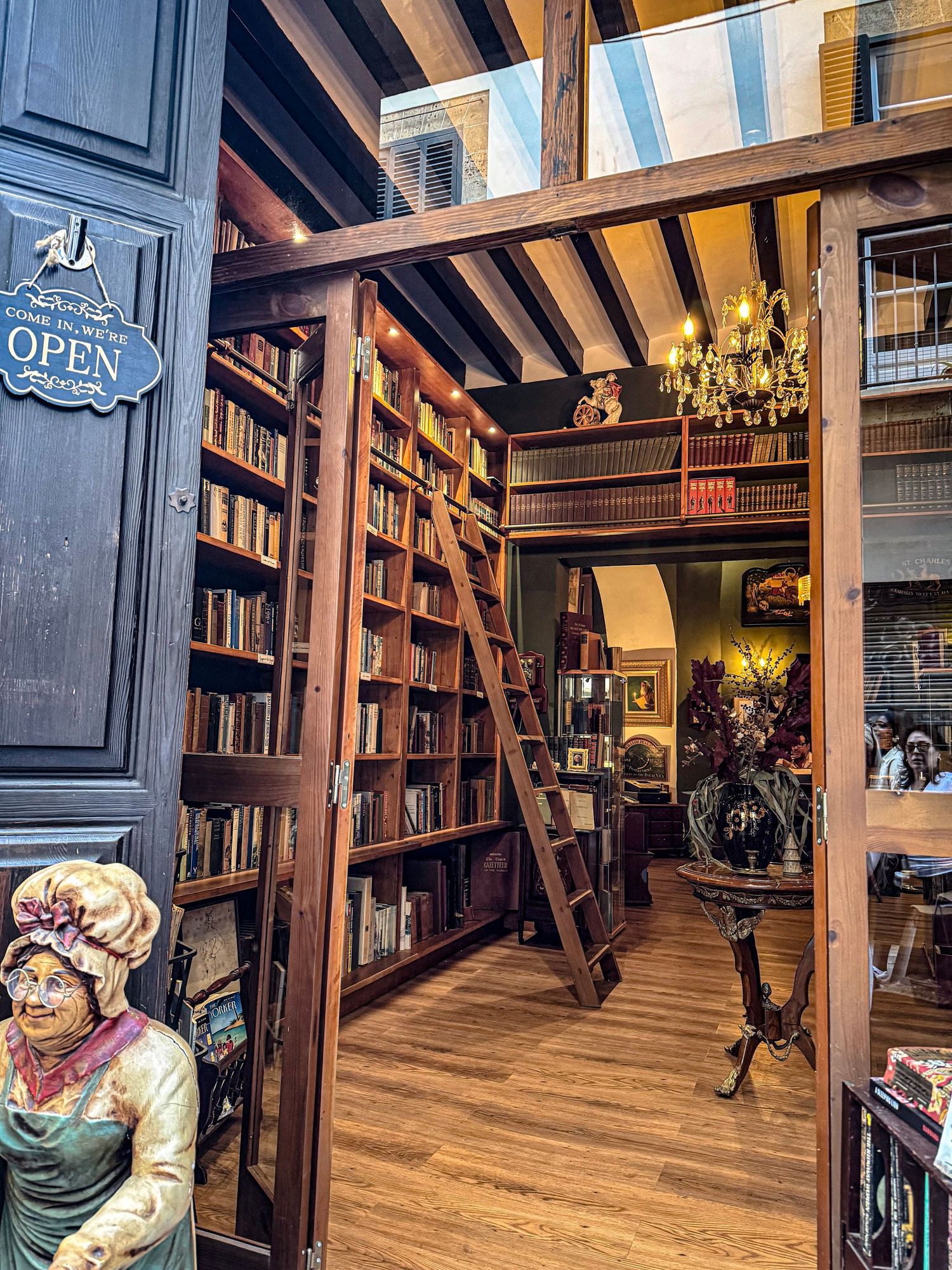 Interior view of an old bookstore with wooden bookshelves, ladders, and antique decorative elements.