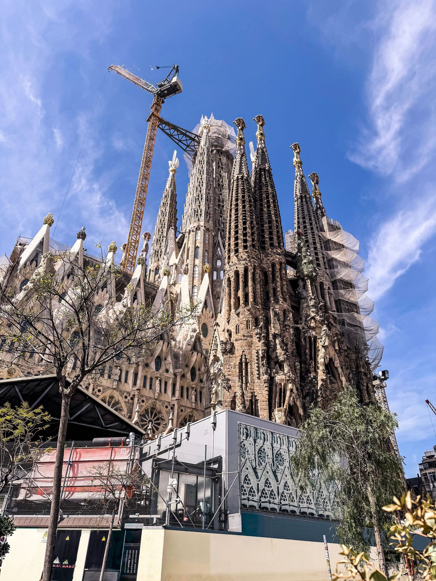 The iconic Sagrada Familia basilica's ornate spires and towers reach skyward against a bright blue sky in Barcelona, Spain.