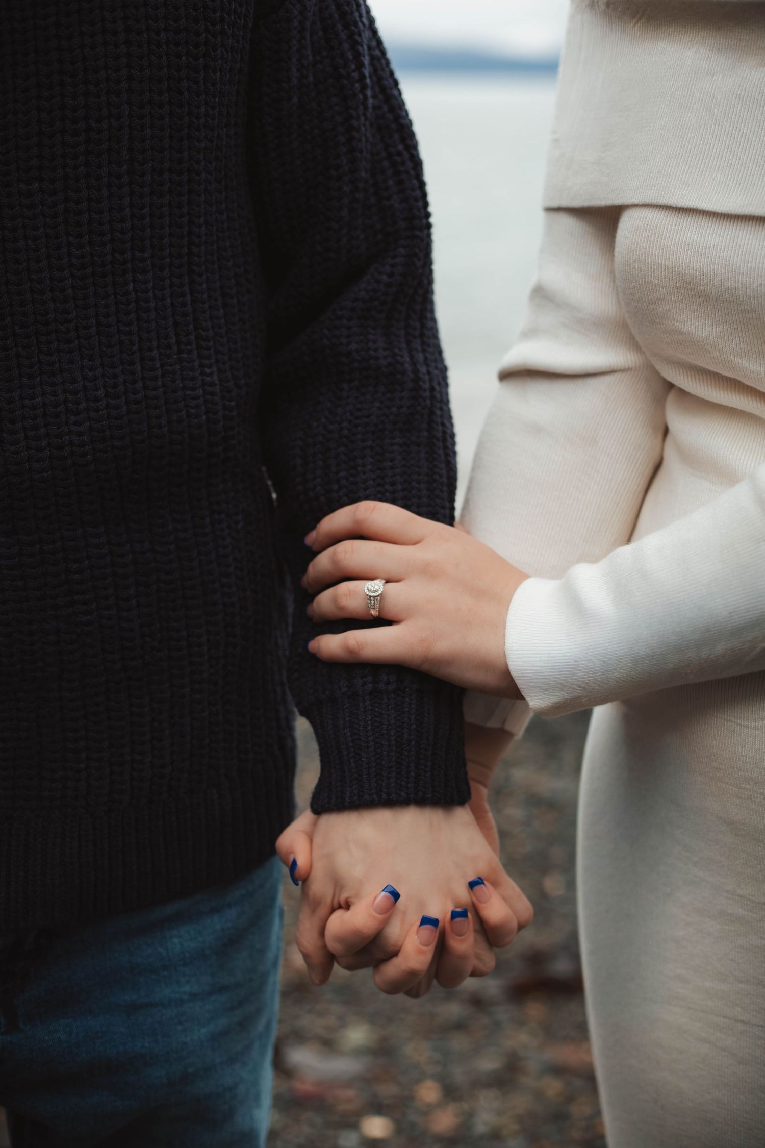 Close-up shot of two people holding hands with one wearing a black sweater and the other in white clothing.