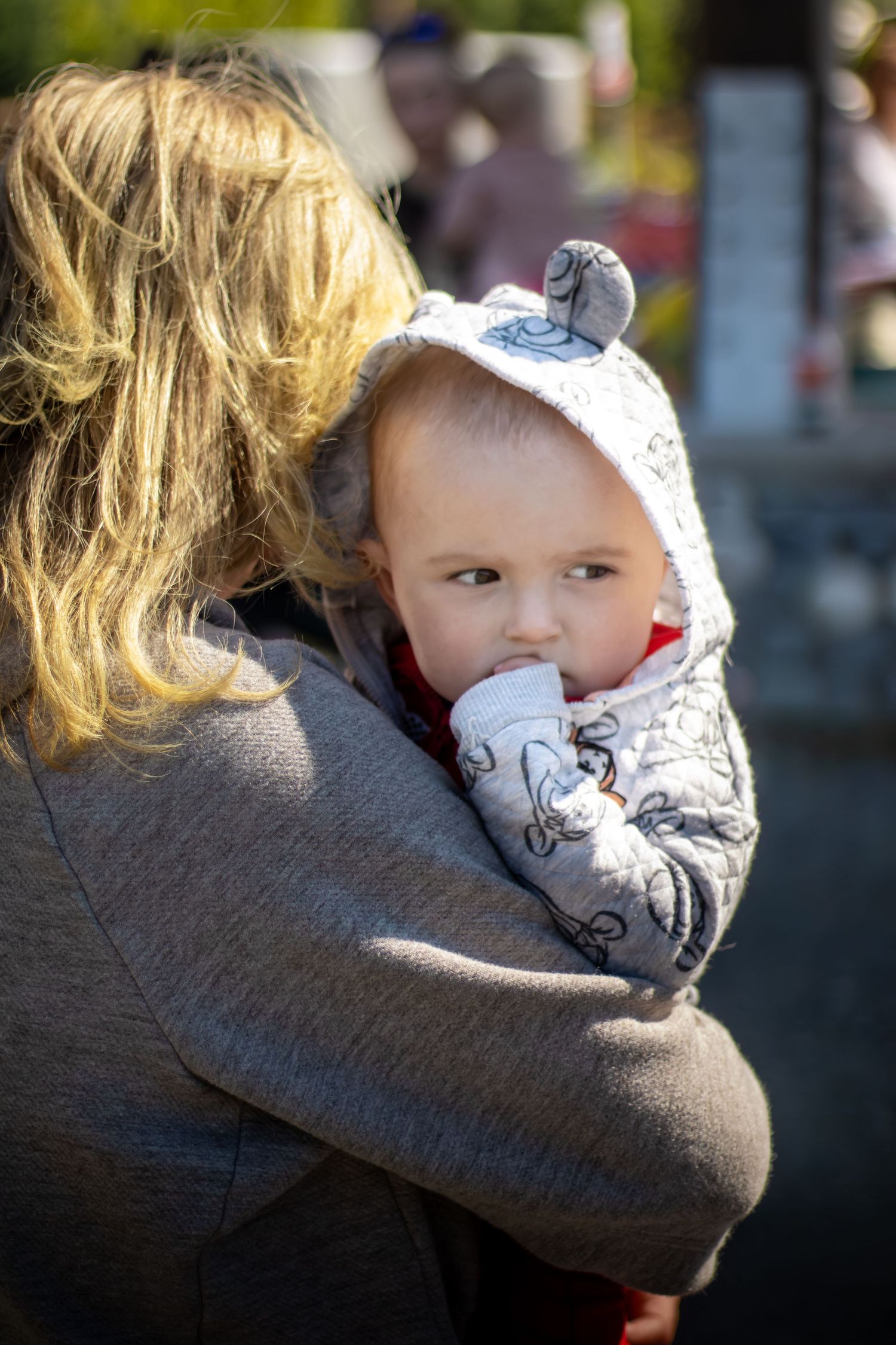 Child wearing gray sweater being held in a warm embrace.
