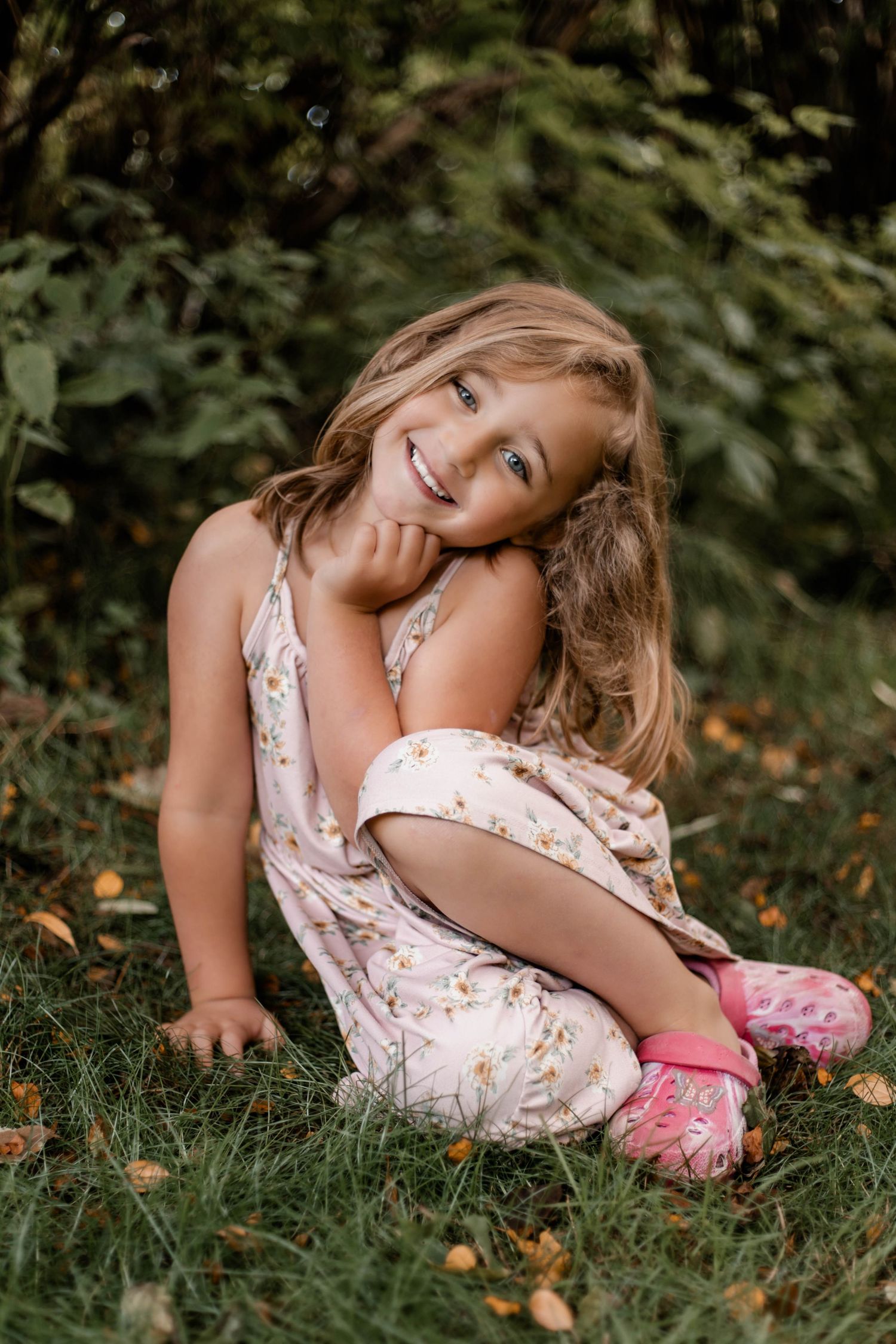 A playful sequence of someone rolling in the grass wearing a floral dress and pink shoes on a summer day.