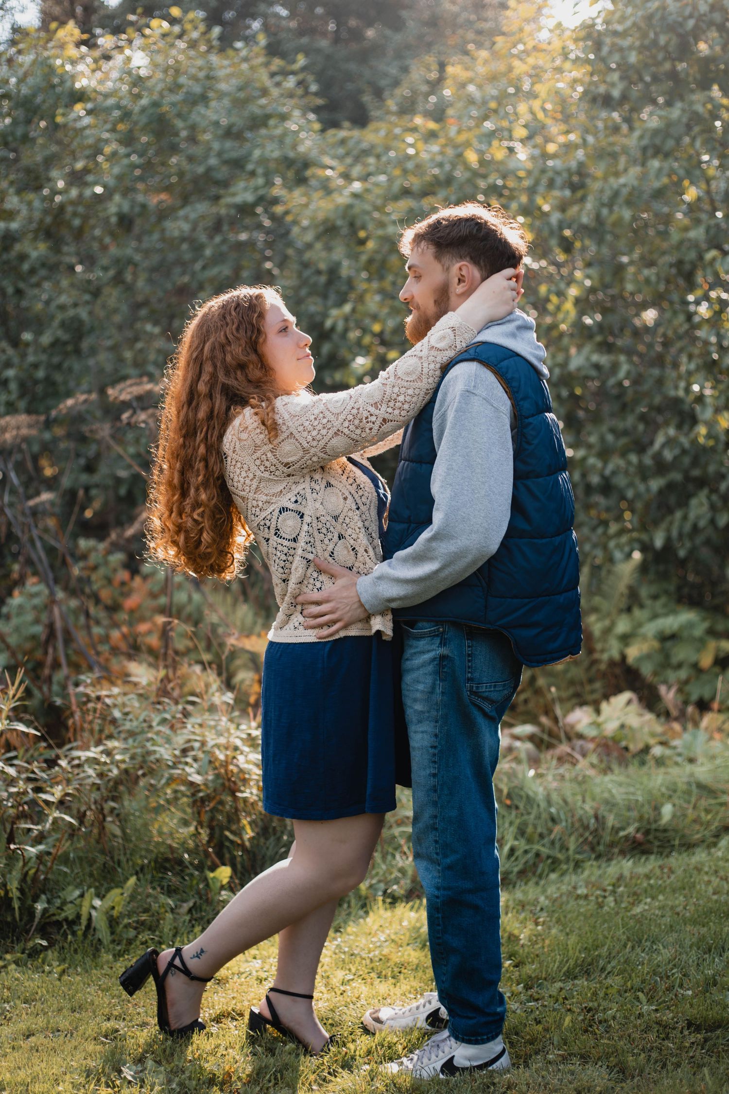 A playful couple dances in a sunny garden setting wearing matching casual outfits.
