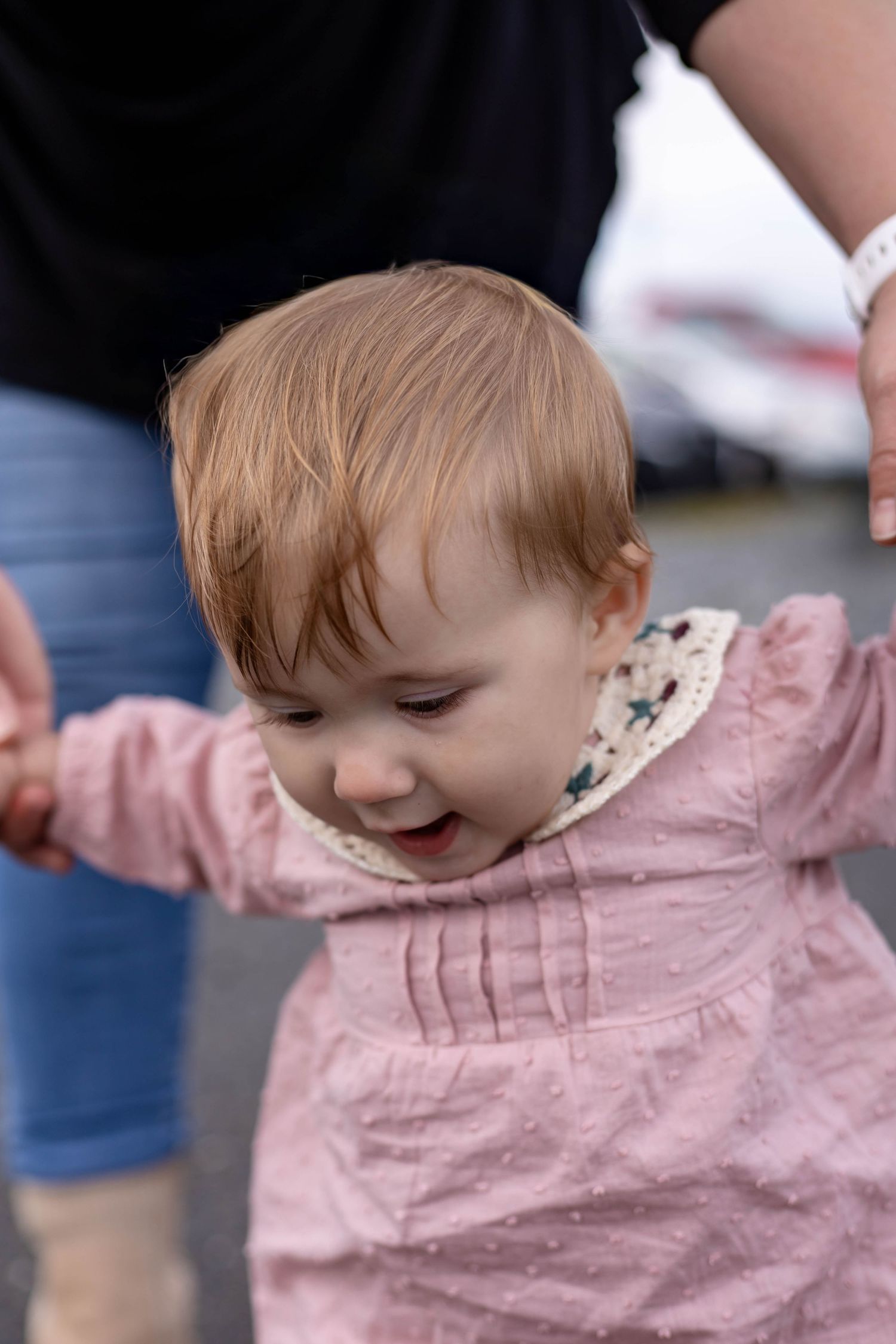 Small child in pink dress smiles while playing outdoors.