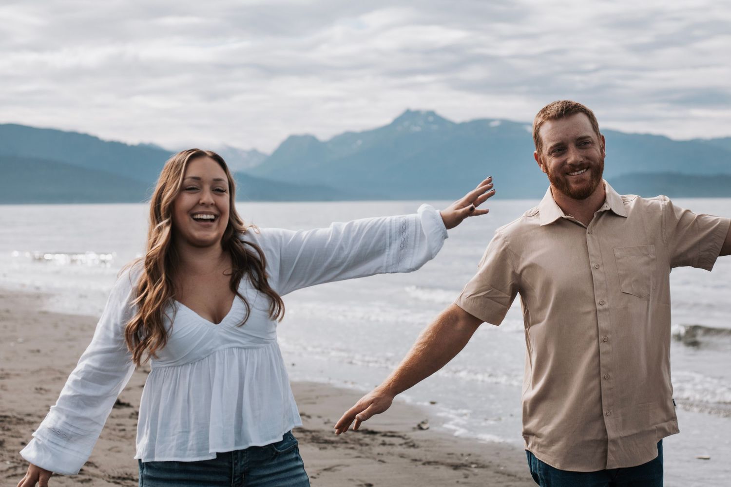 Joyful dance moves on scenic beach with mountains in background in Alaska