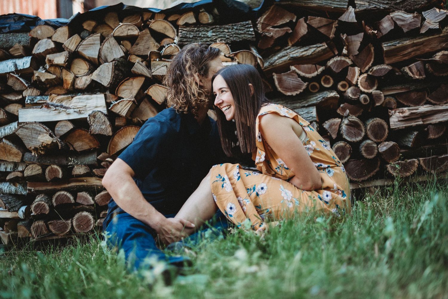 Romantic couple sharing a tender moment sitting together against a rustic firewood stack at home in Wisconsin