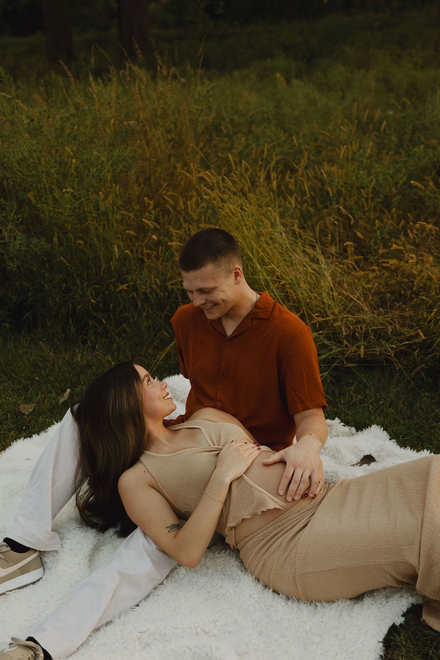 Couple sharing intimate moment on picnic blanket in golden field.