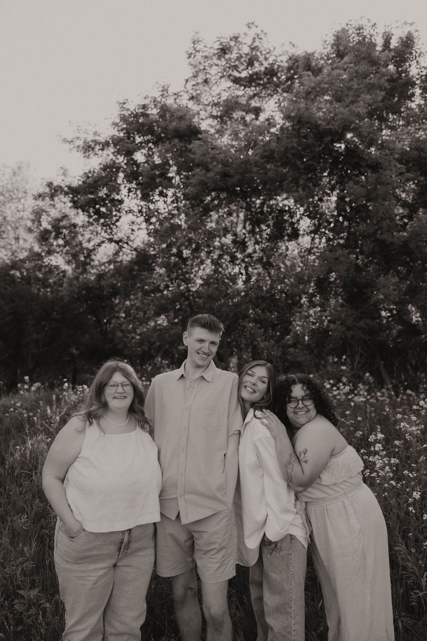A black and white group photo showing five people posed casually together outdoors.