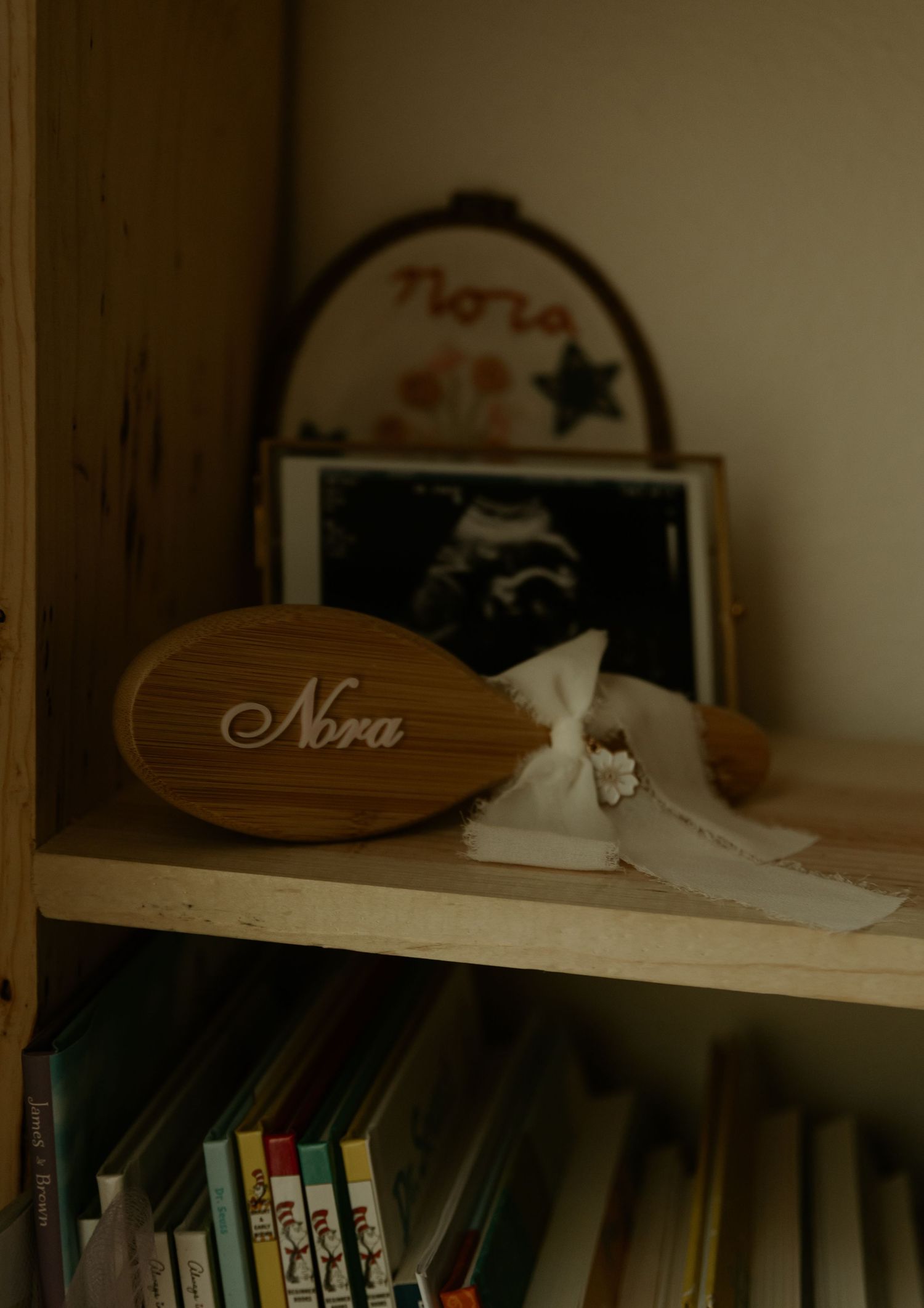 Wooden shelf displaying decorative name signs and personal mementos in soft focus.