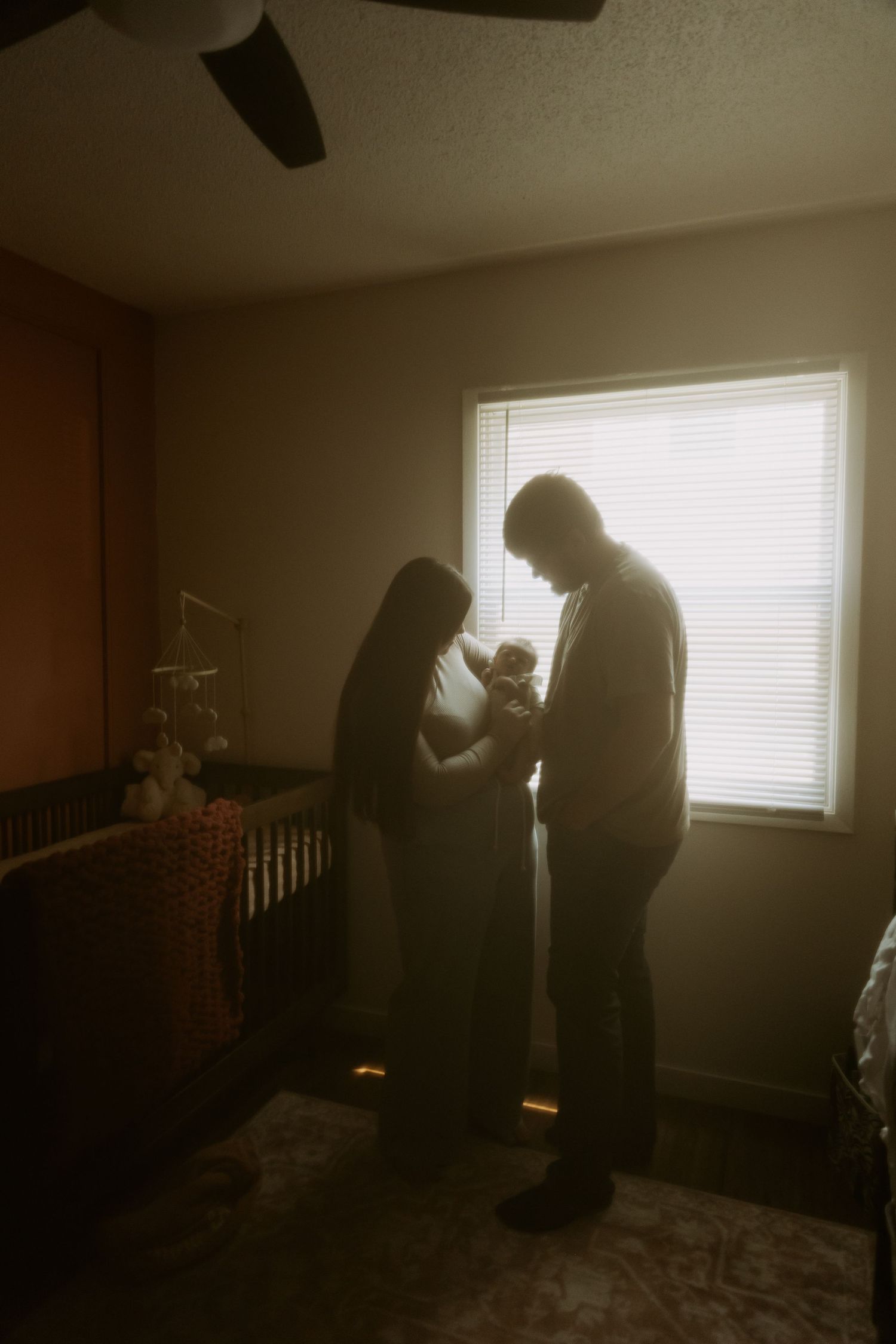 Silhouettes against a window create an intimate moment in a nursery setting.