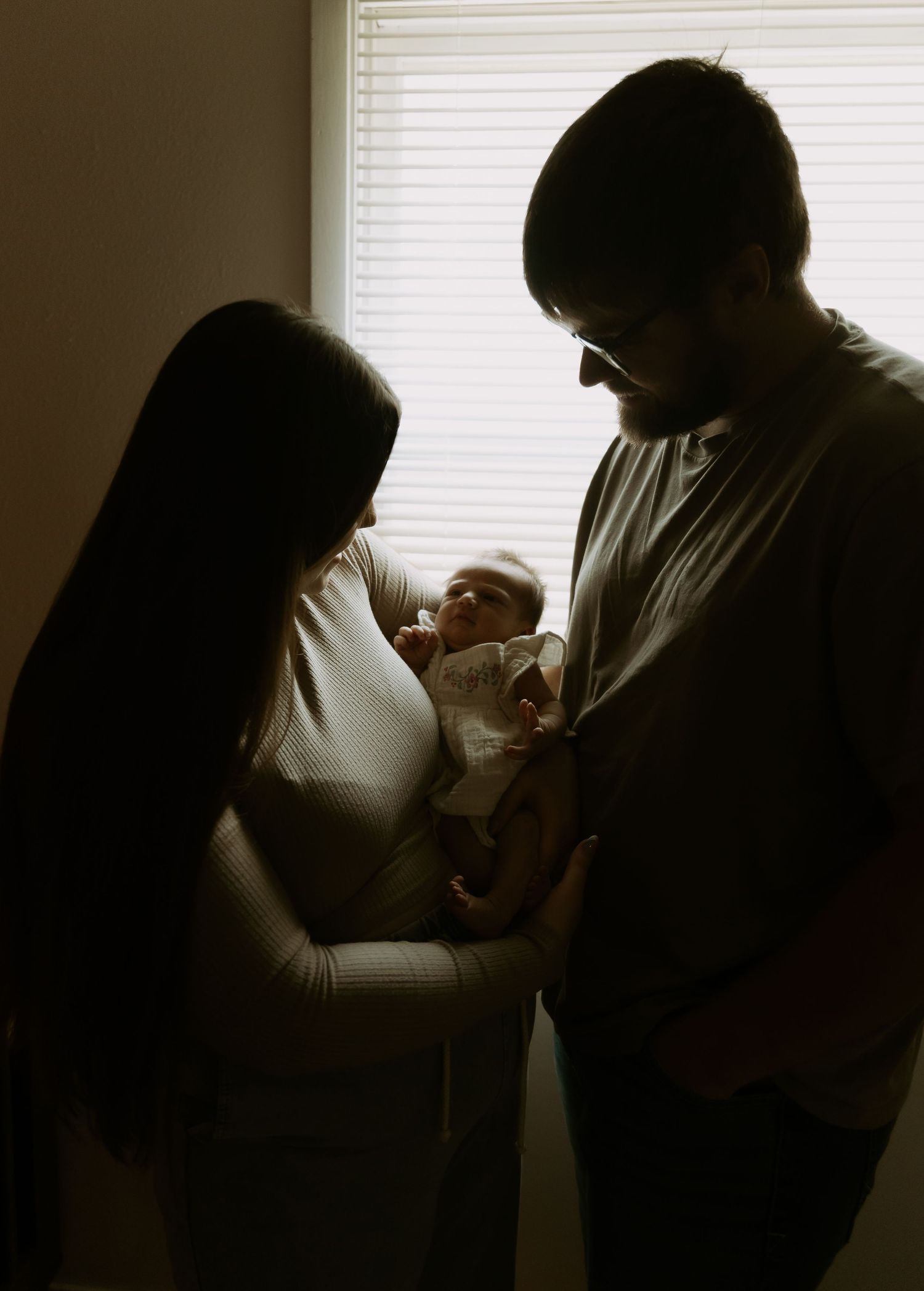 Silhouetted figures in intimate indoor setting with window light creating dramatic shadows.