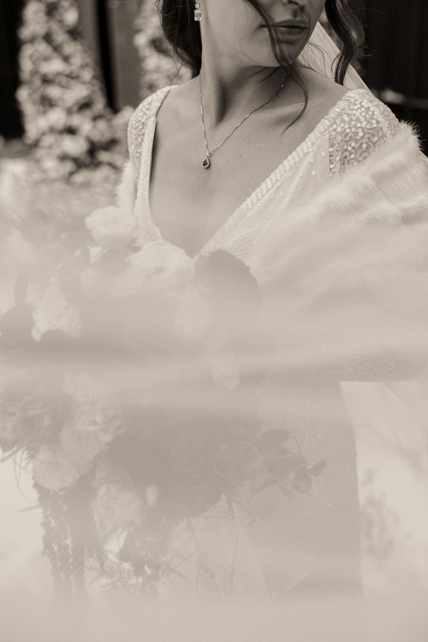 Black and white artistic bridal portrait showing delicate lace details and a necklace against a dreamy ethereal background.