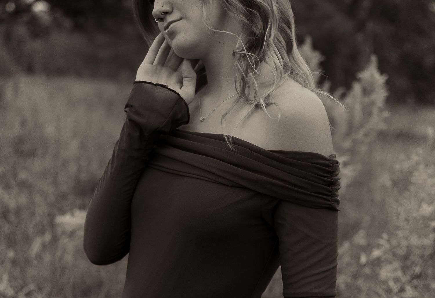 A couple embraces in a romantic black and white photoshoot across multiple artistic poses in a field.