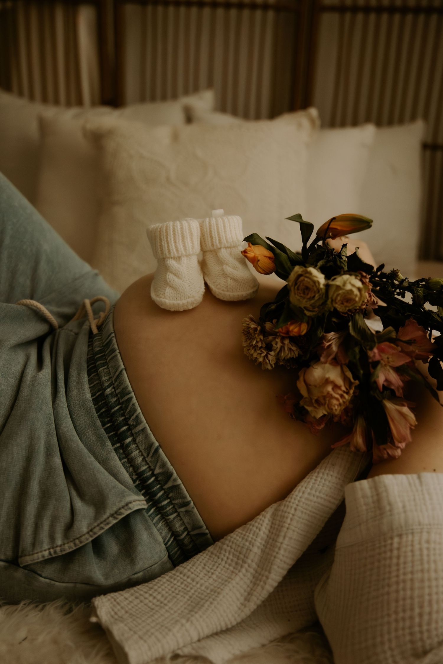 Soft floral arrangement with dried flowers against white bedding and denim fabric.