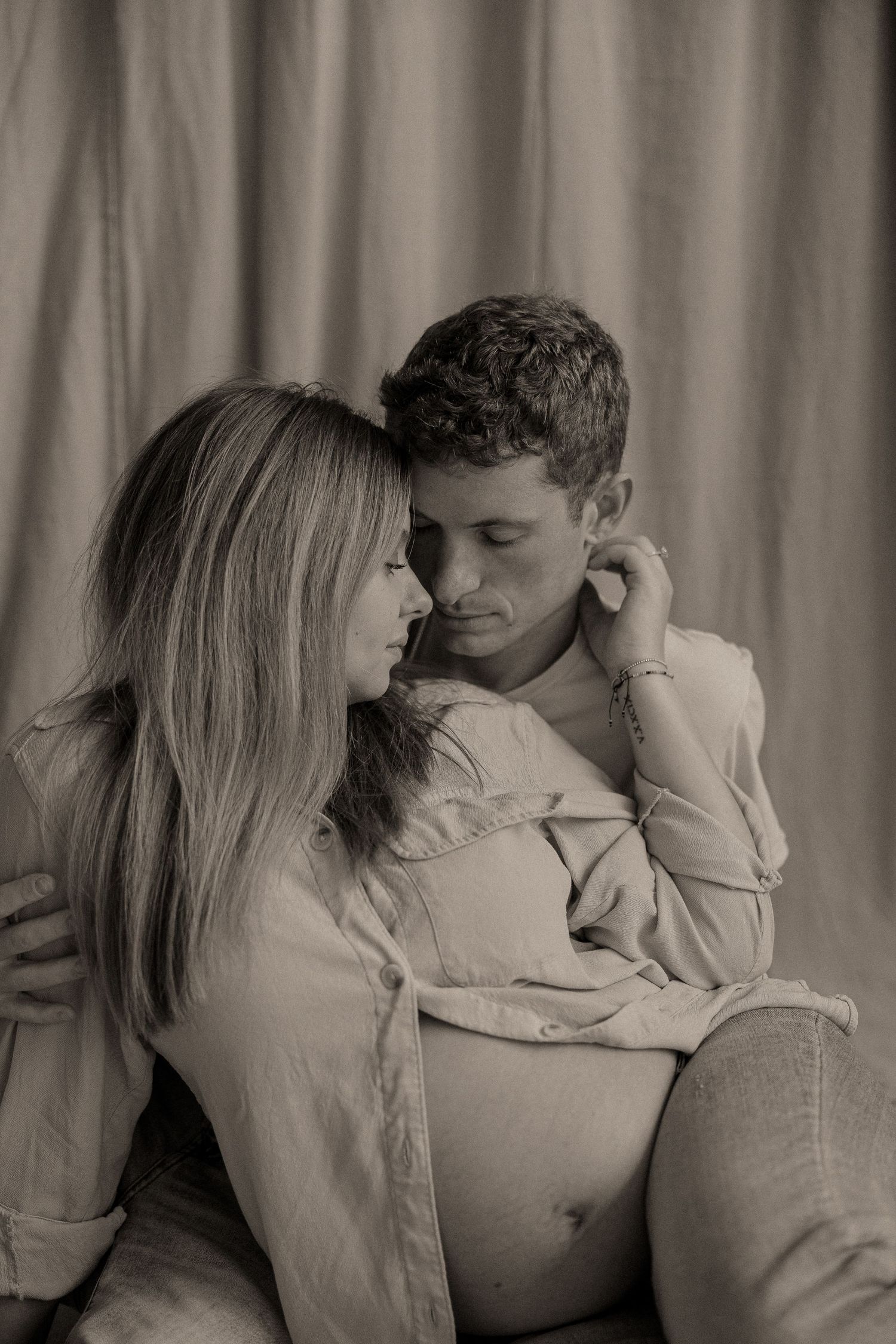 A romantic black and white portrait of a couple in intimate embrace wearing light colored sweaters.