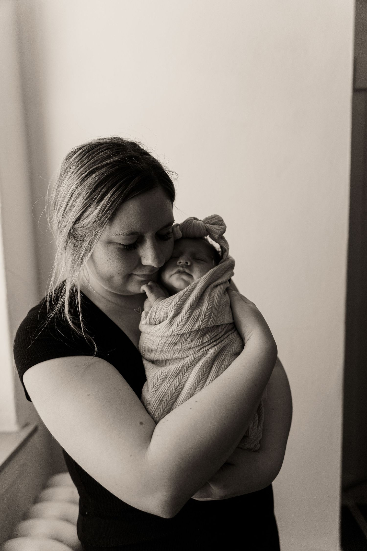 Emotional black and white portrait showing tender embrace in minimalist setting.