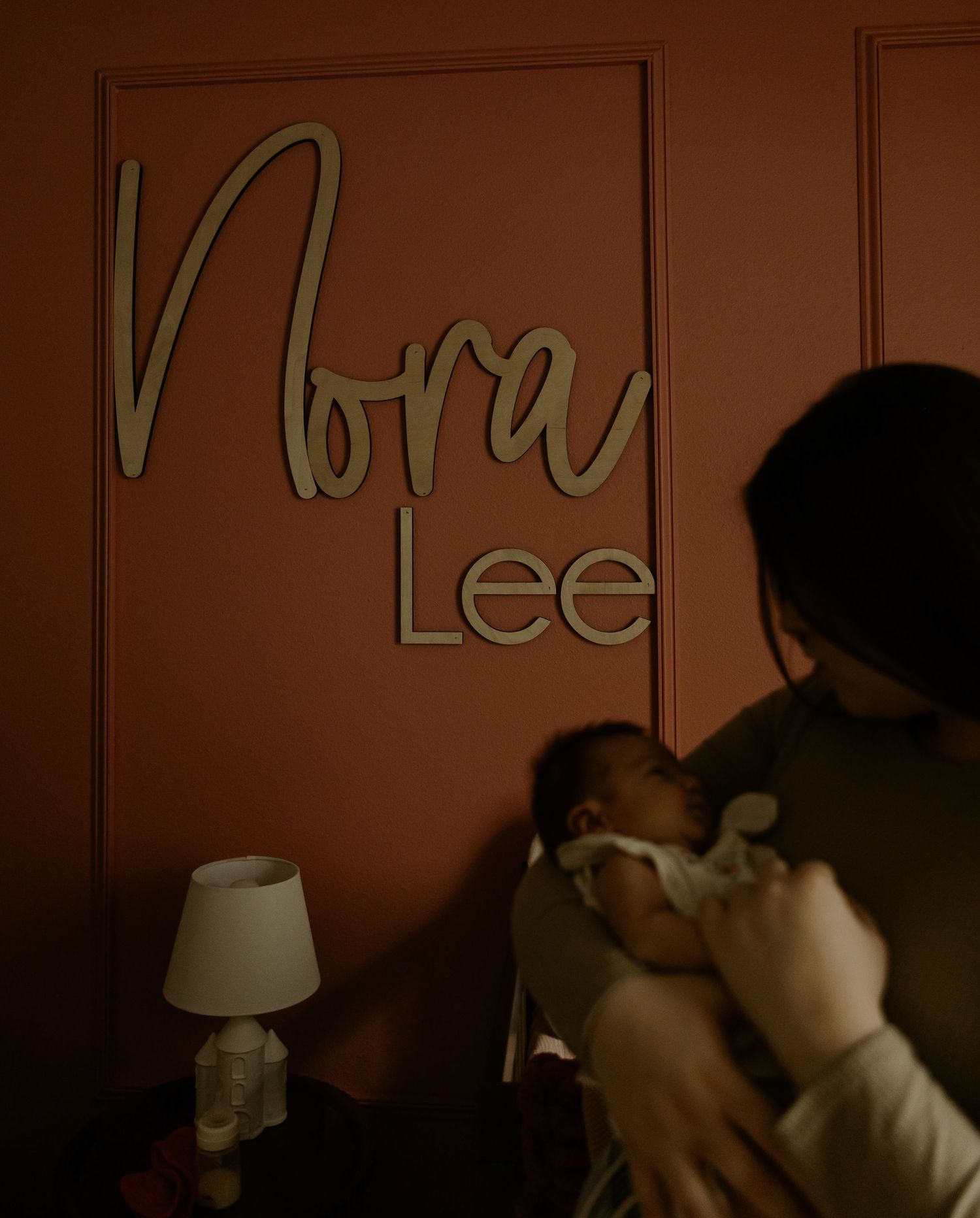 Wall decorated with cursive text in muted lighting creates a warm nursery atmosphere.