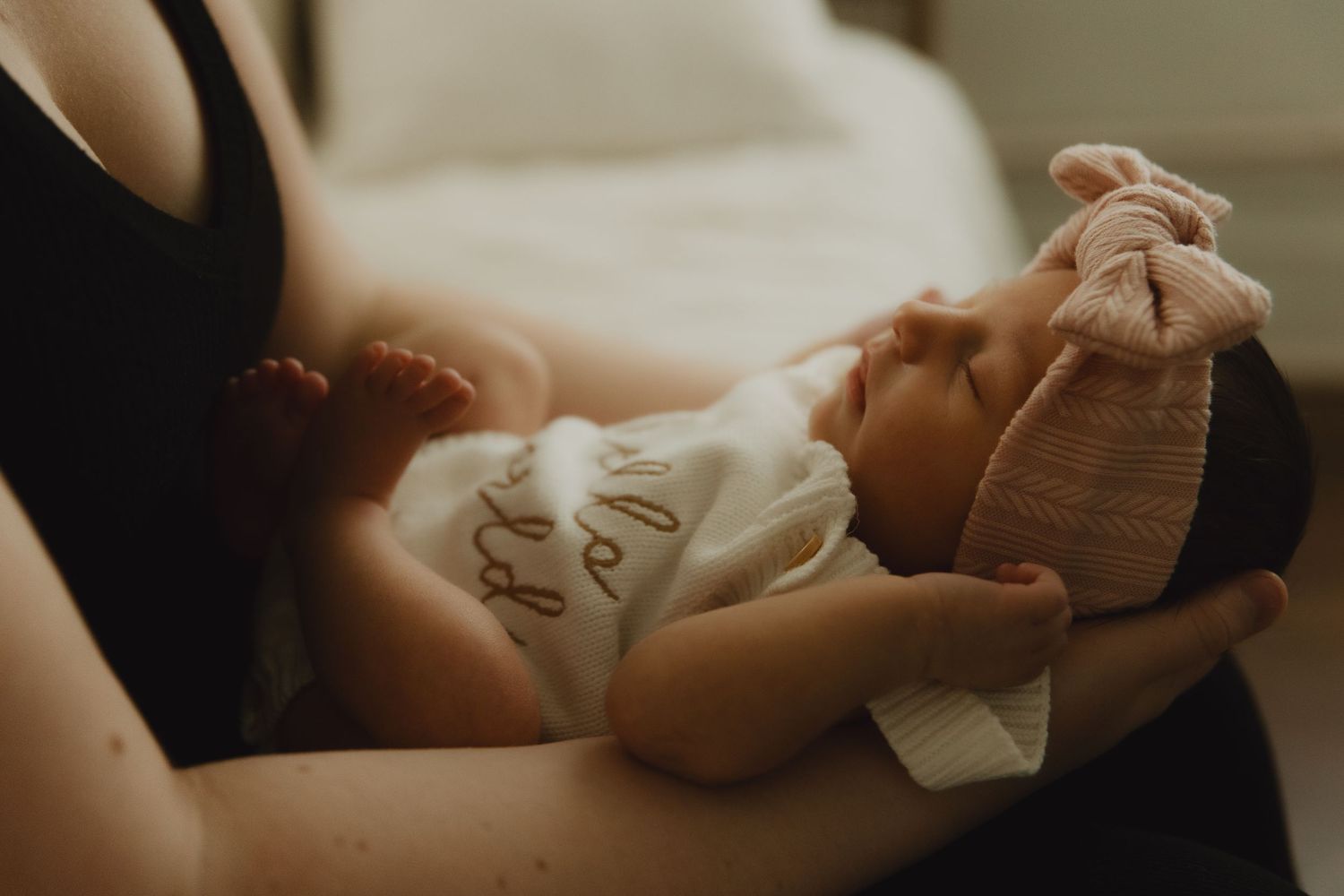 Intimate newborn photography session with soft white bedding and natural light.
