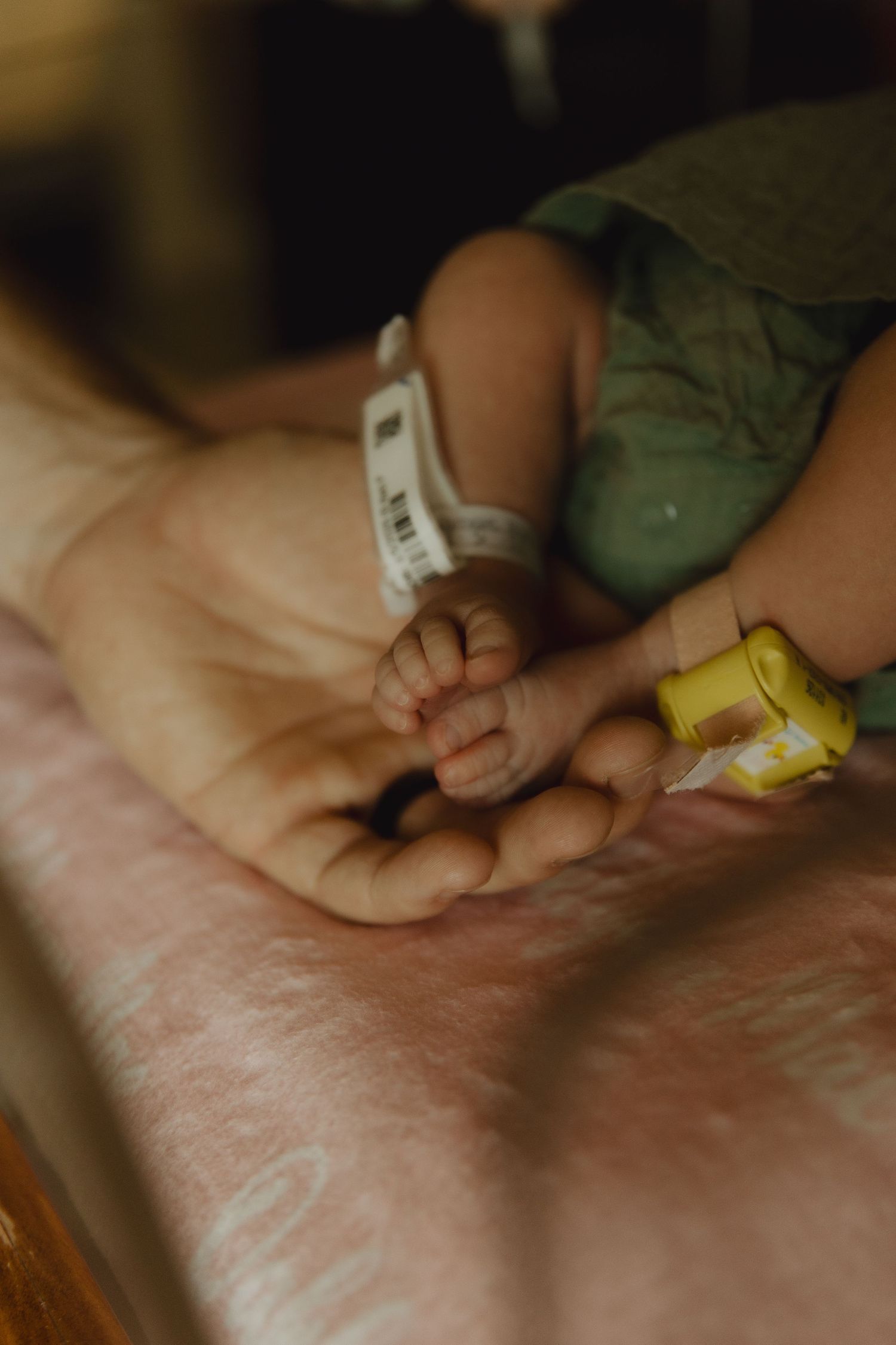 Close-up of tiny baby hand holding hospital identification bracelet.