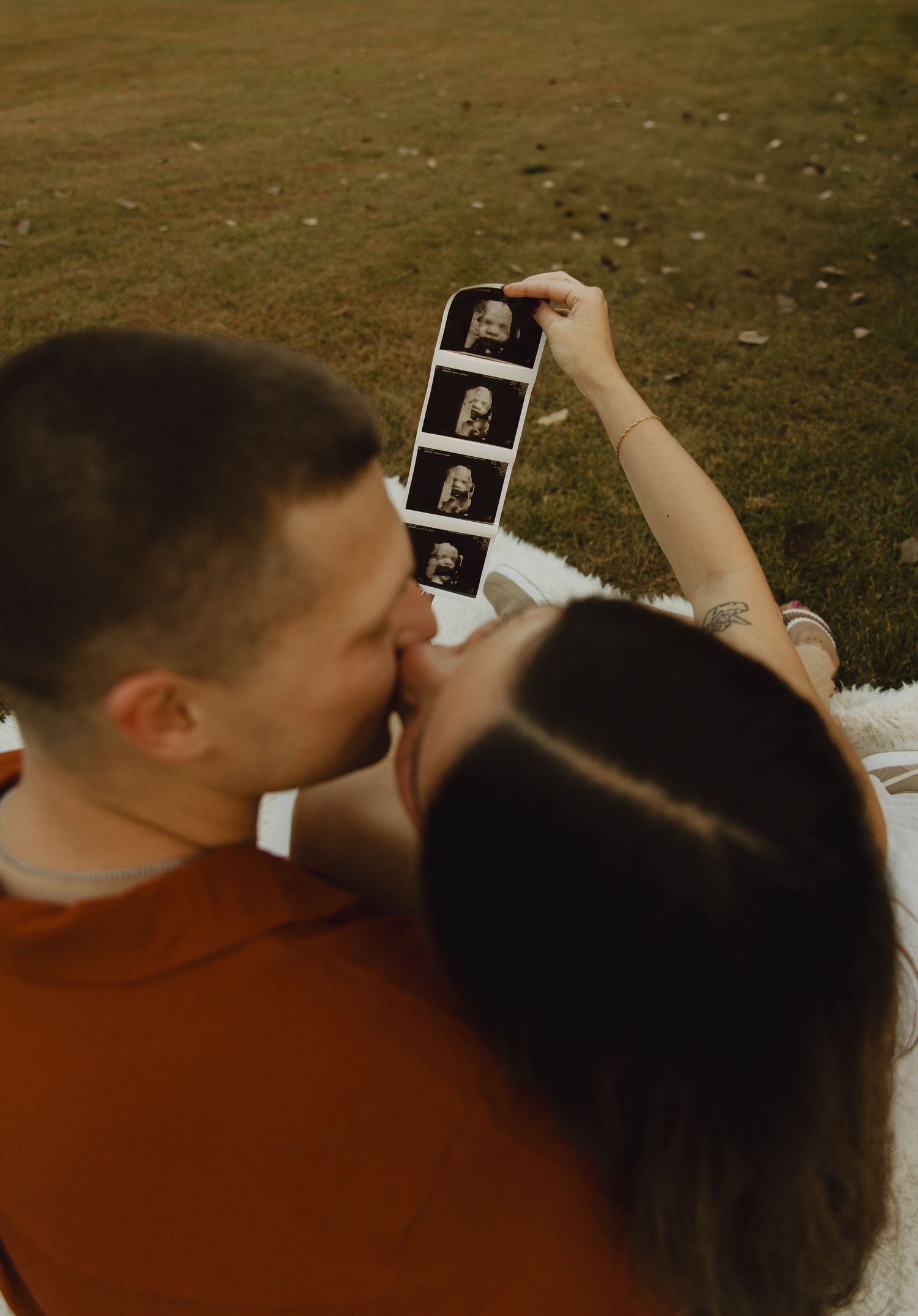 Couple looking at ultrasound photos together during outdoor maternity session.