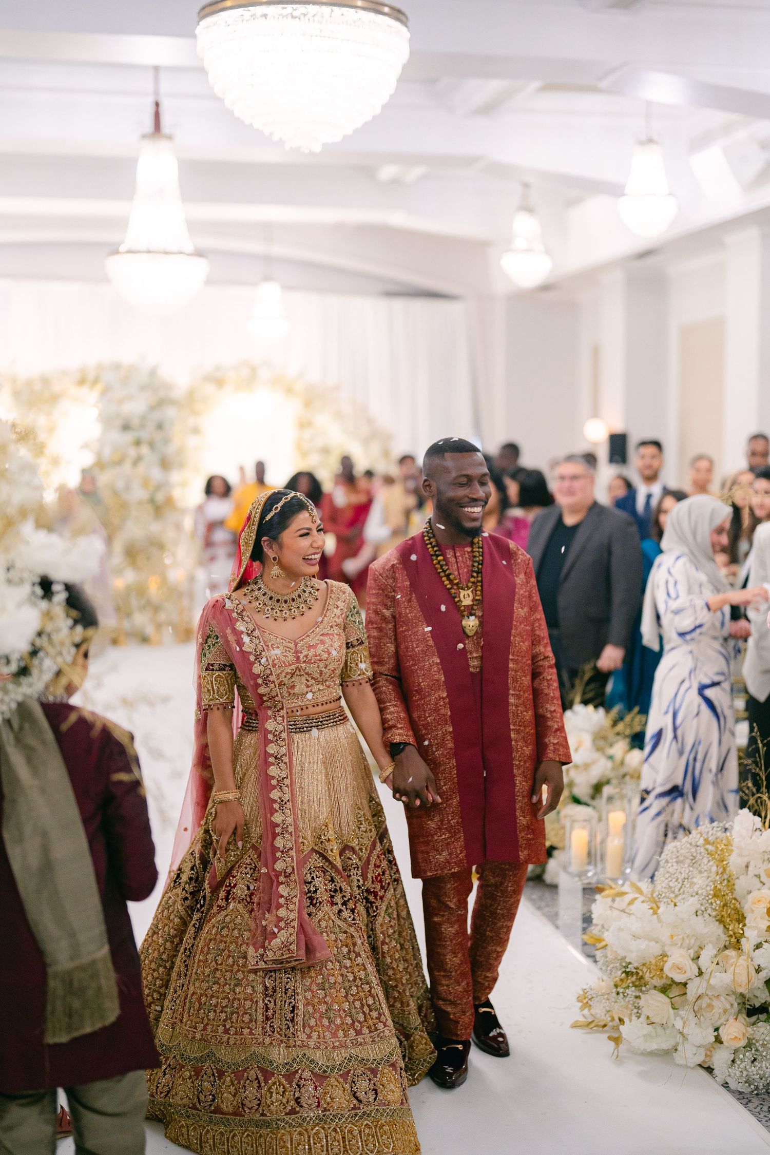 Wedding celebration in an elegant white reception hall with floral decorations.