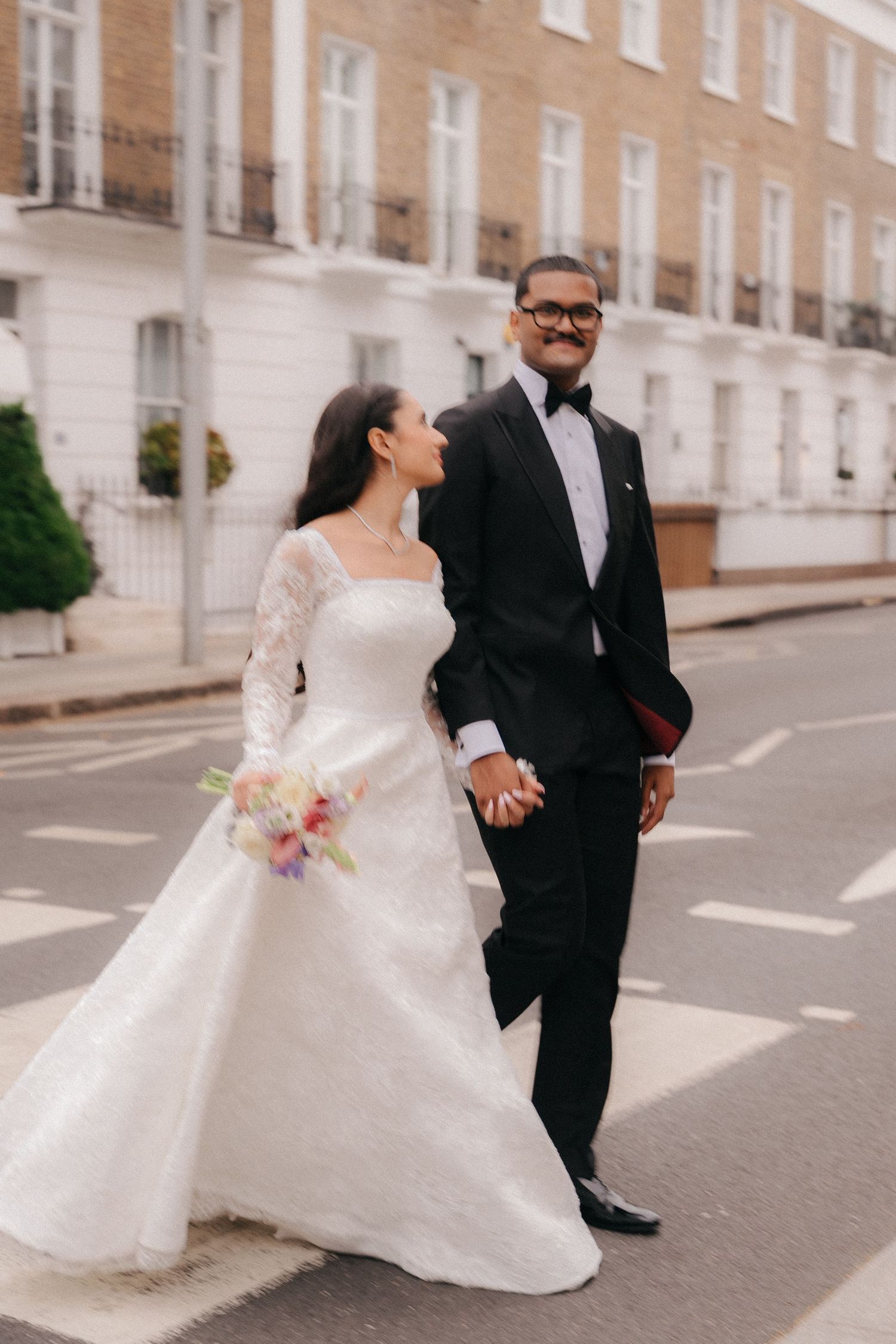 Couple shares joyful moment on London street during wedding portraits.
