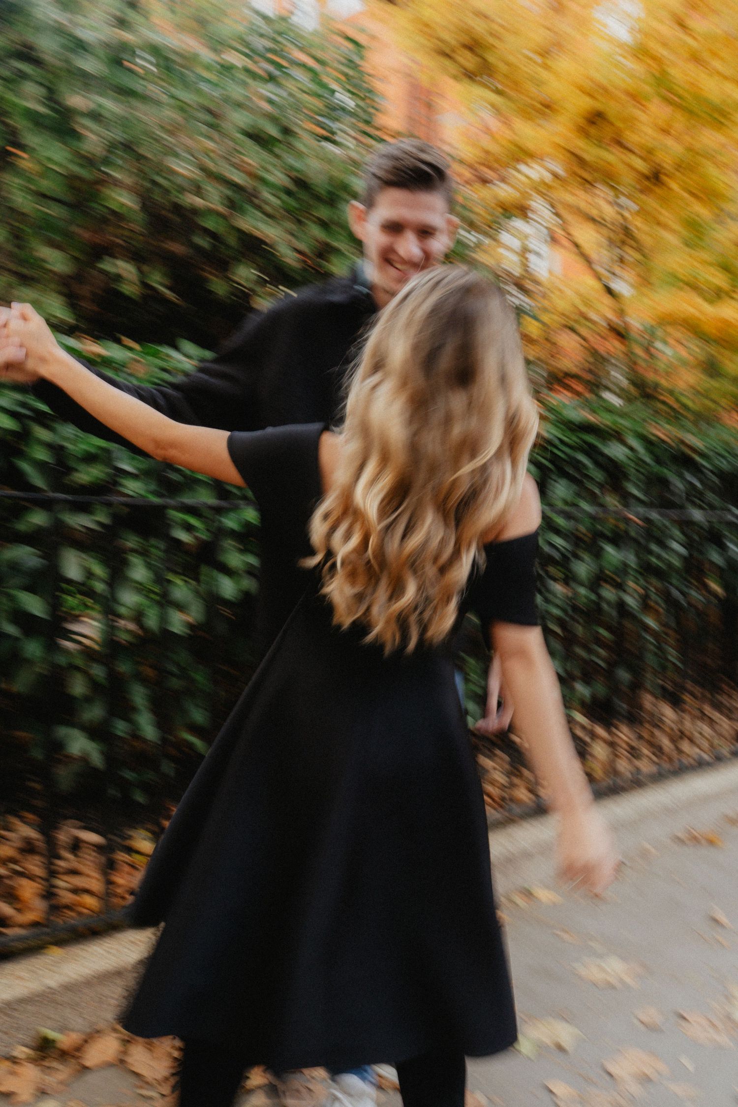 Playful autumn couple photoshoot with golden foliage backdrop.