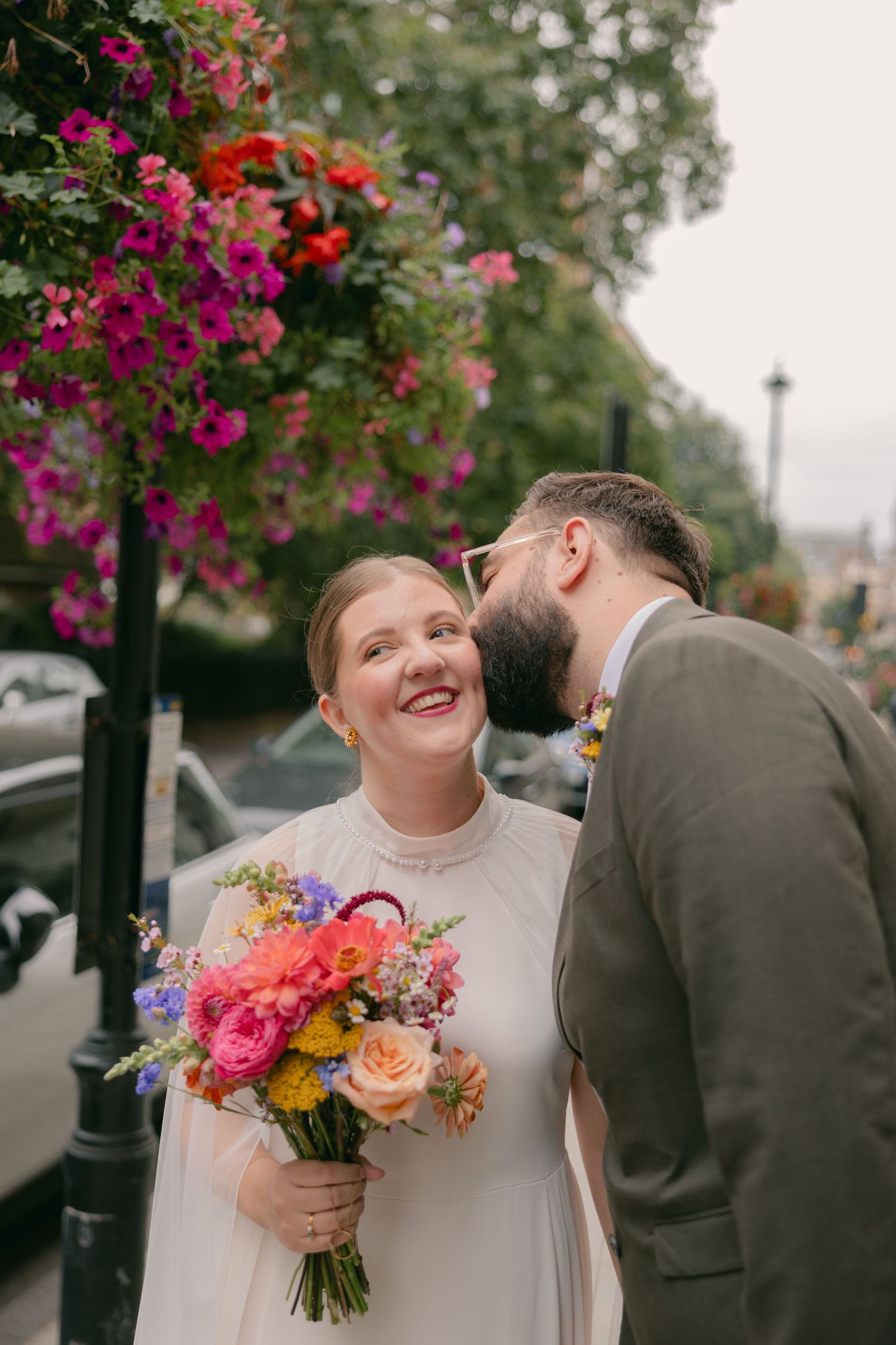 A joyful moment captured under blooming pink flowers on a city street.
