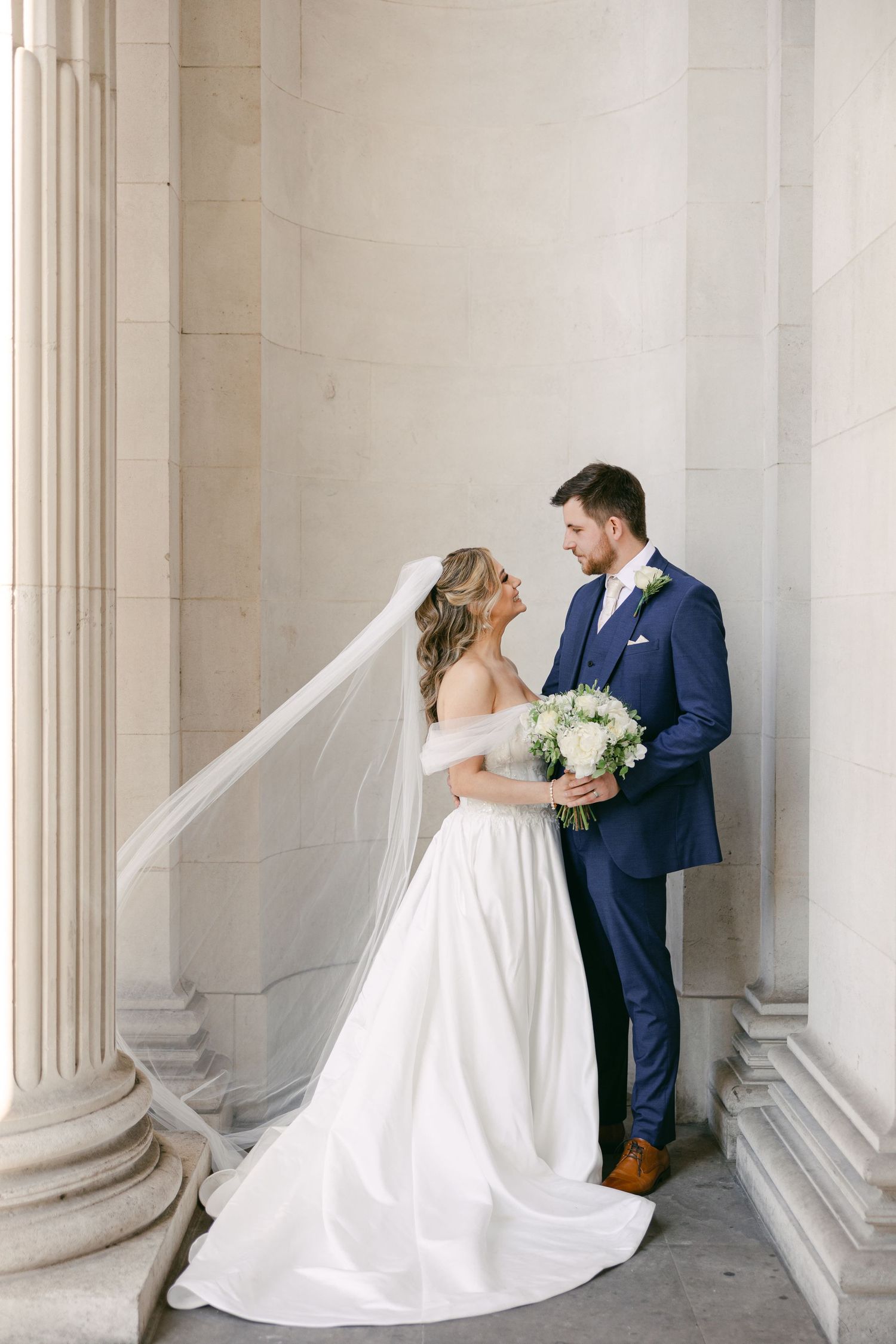 Wedding portraits taken in an elegant colonnade with classical architecture. Old Marylebone Townhall